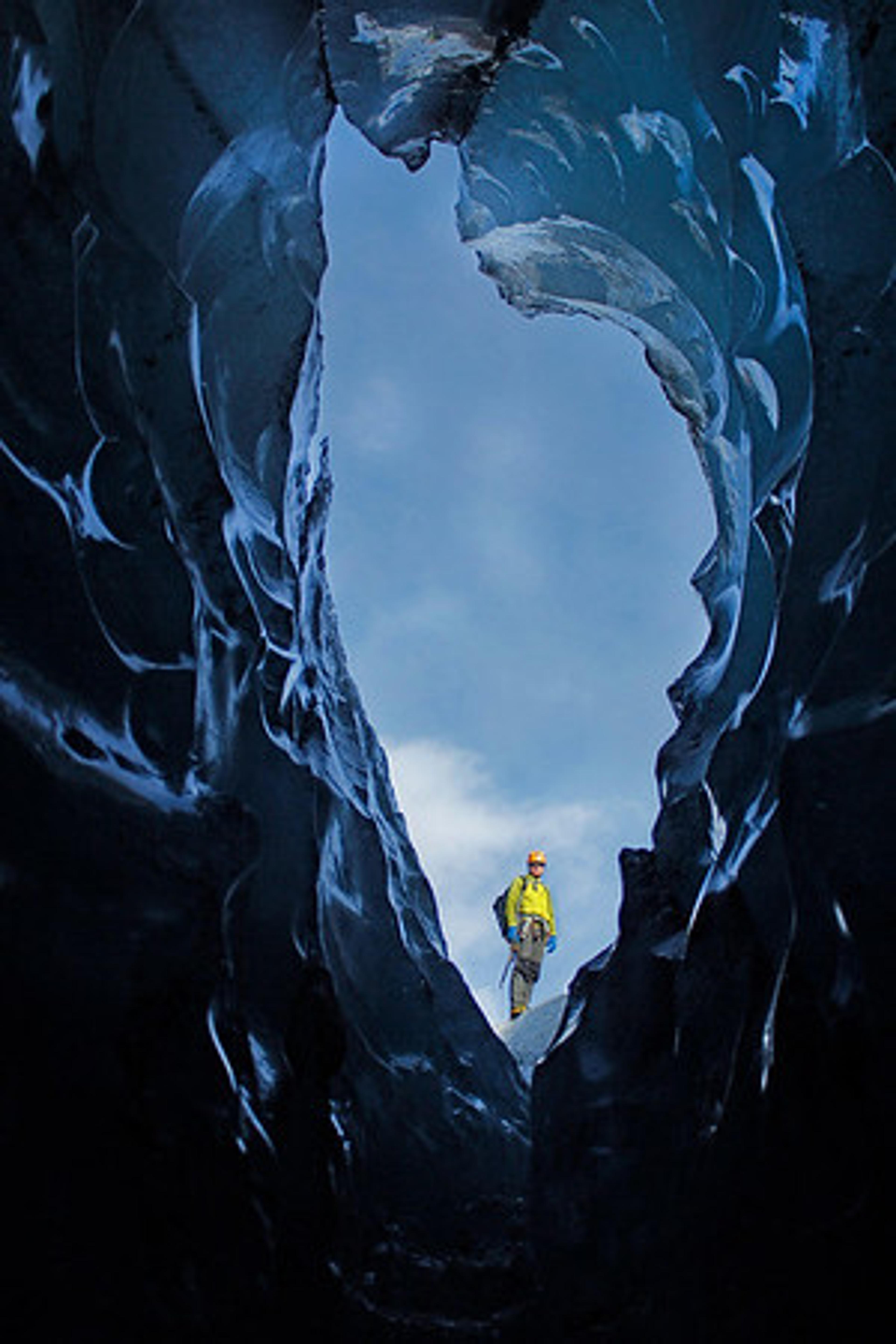 A man seen through a hole in the roof of an ice cave