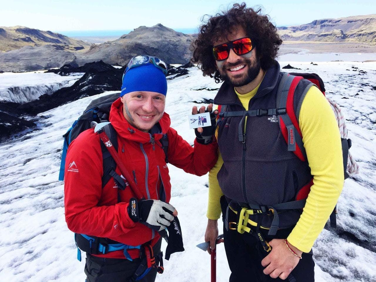 Two men on a hike smiling with a beautiful scenery of Iceland behind them