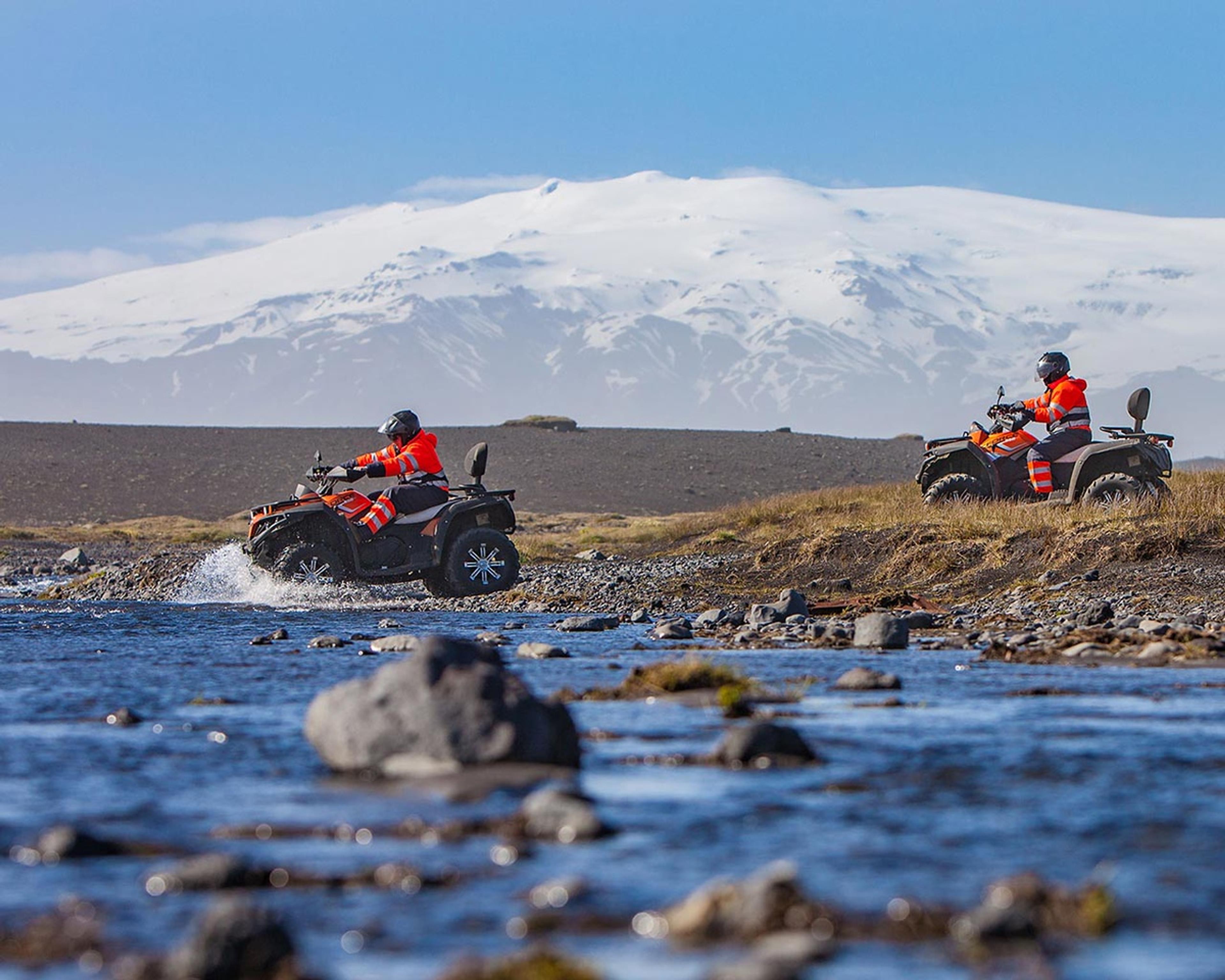 Two atv quads crossing a river and Eyjafjallajökulll in the background