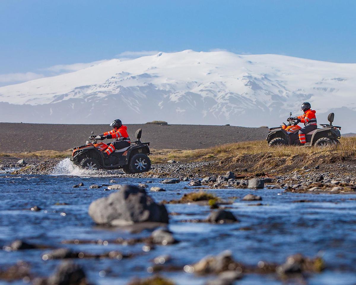 Two atv quads crossing a river and Eyjafjallajökulll in the background