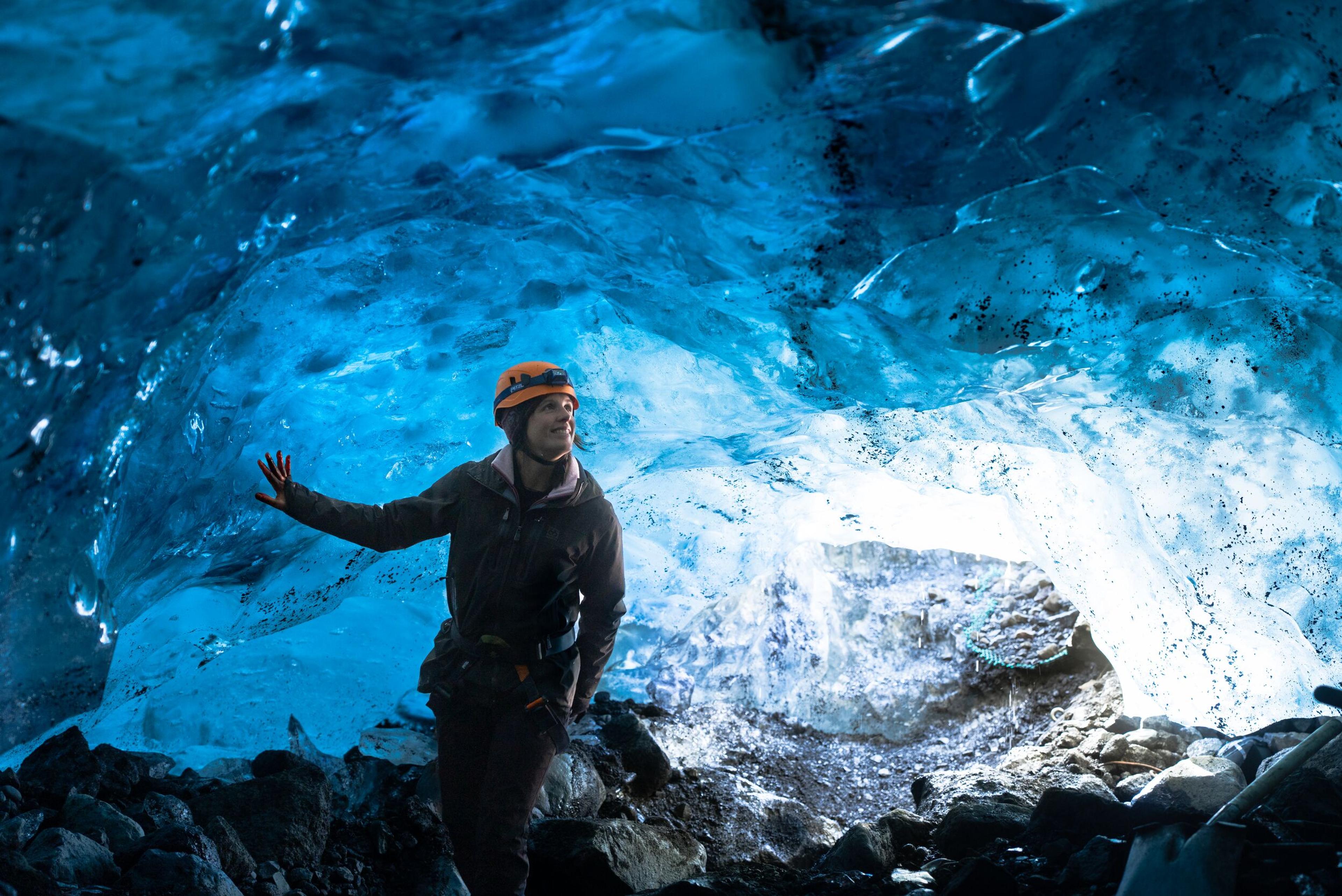 A person wearing a helmet, standing inside an ice cave at Sólheimajökull glacier