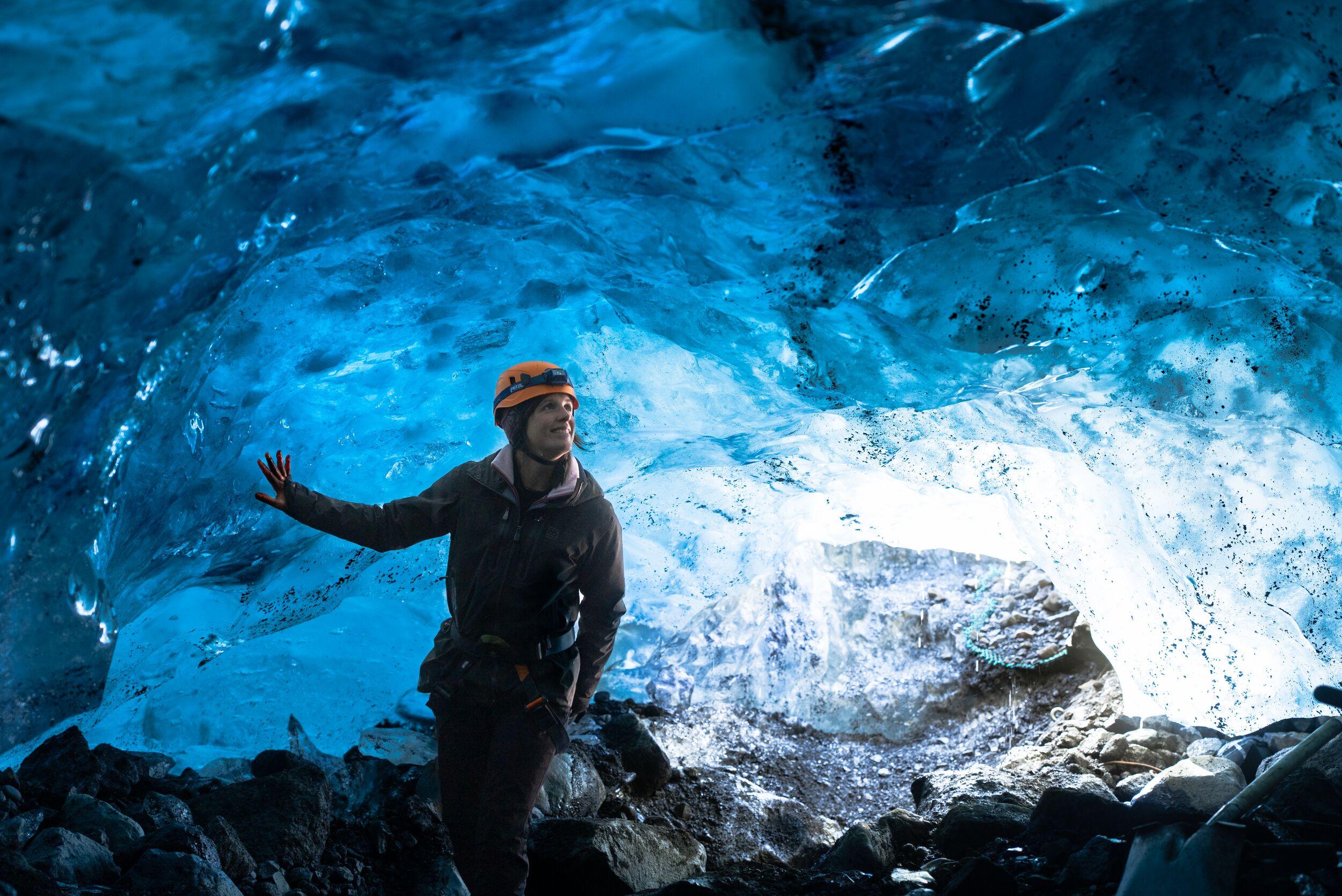 A person wearing a helmet, standing inside an ice cave at Sólheimajökull glacier