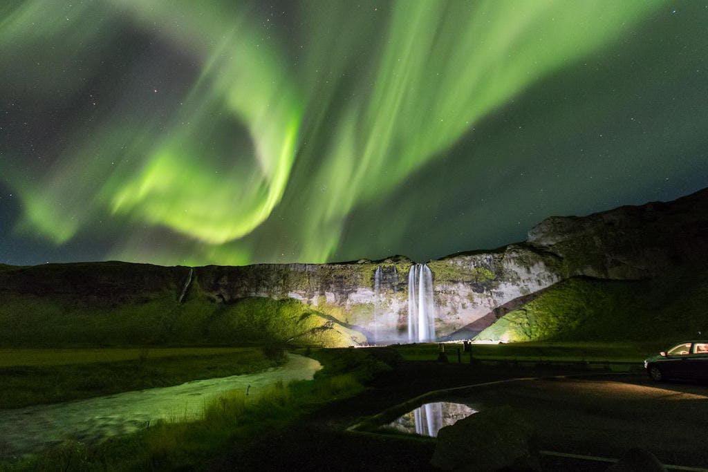 Green aurora borealis over Seljalandsfoss waterfall. Winter is the best time to visit Iceland to see Northern Lights