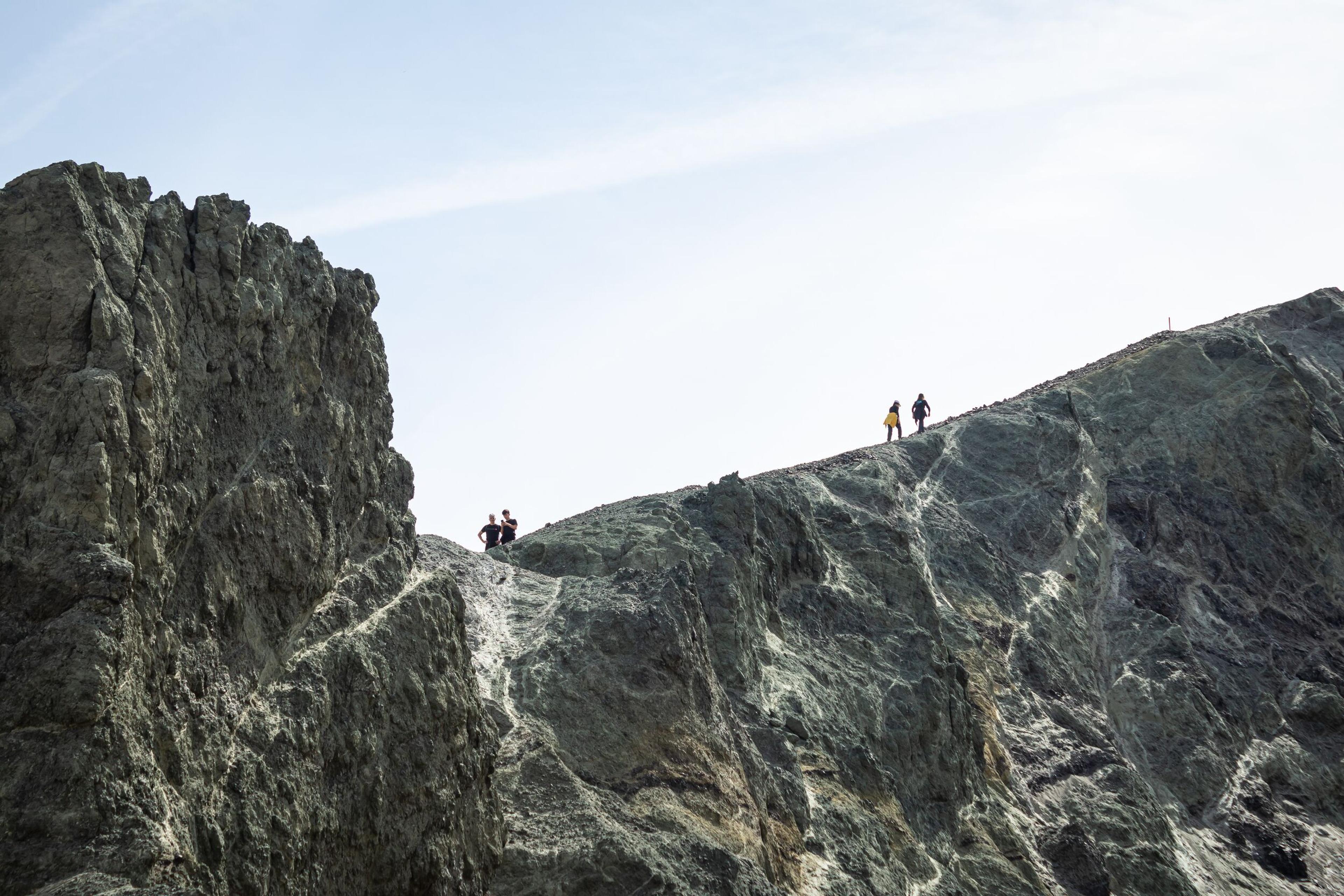 Scenic view of Landmannalaugar's base camp with hikers, geothermal streams, and colorful mountains in the background.