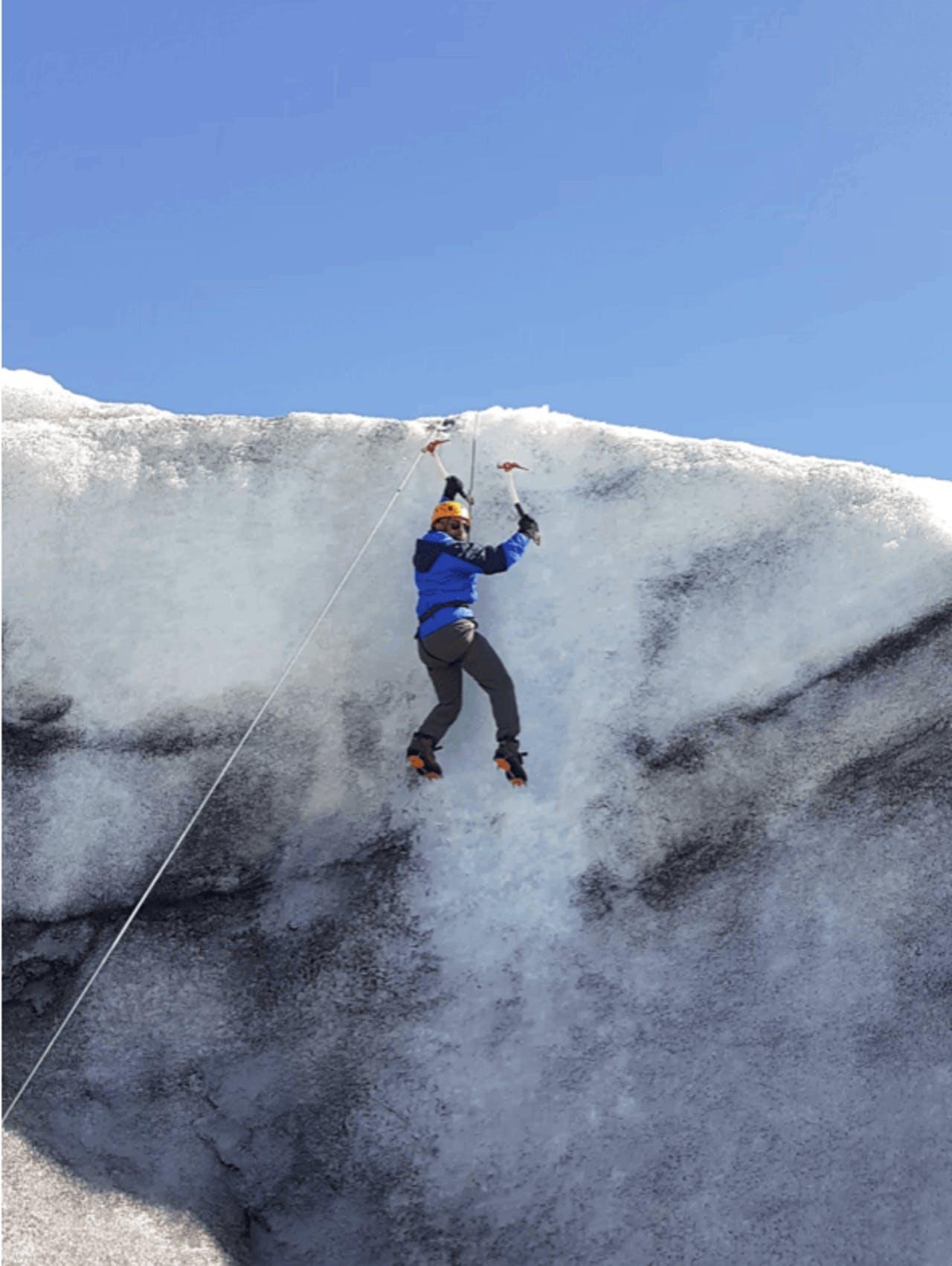A person in a blue jacket climbing on Sólheimajökull