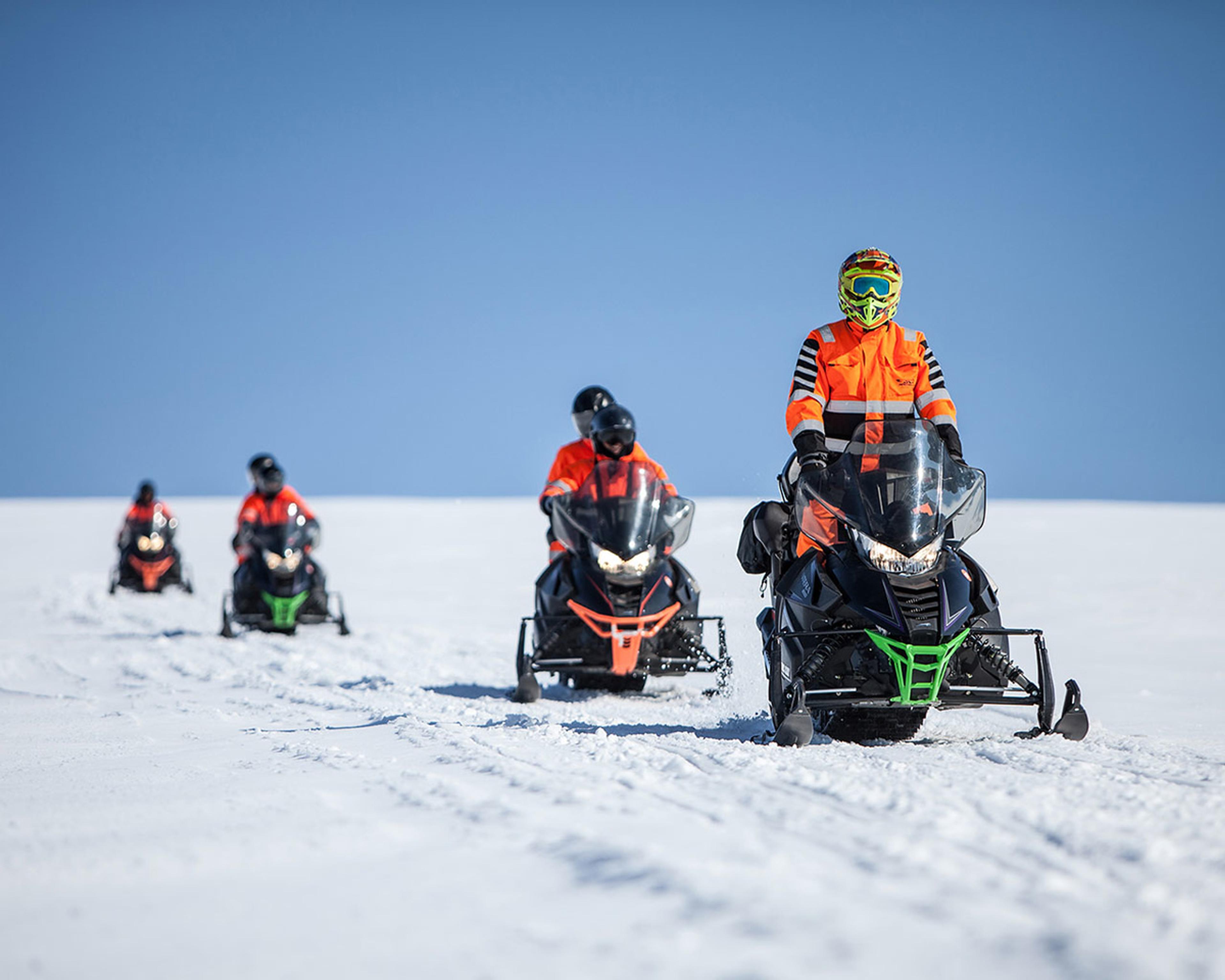 Snowmobiles going higher uo on the glacier on a snow scooter tour