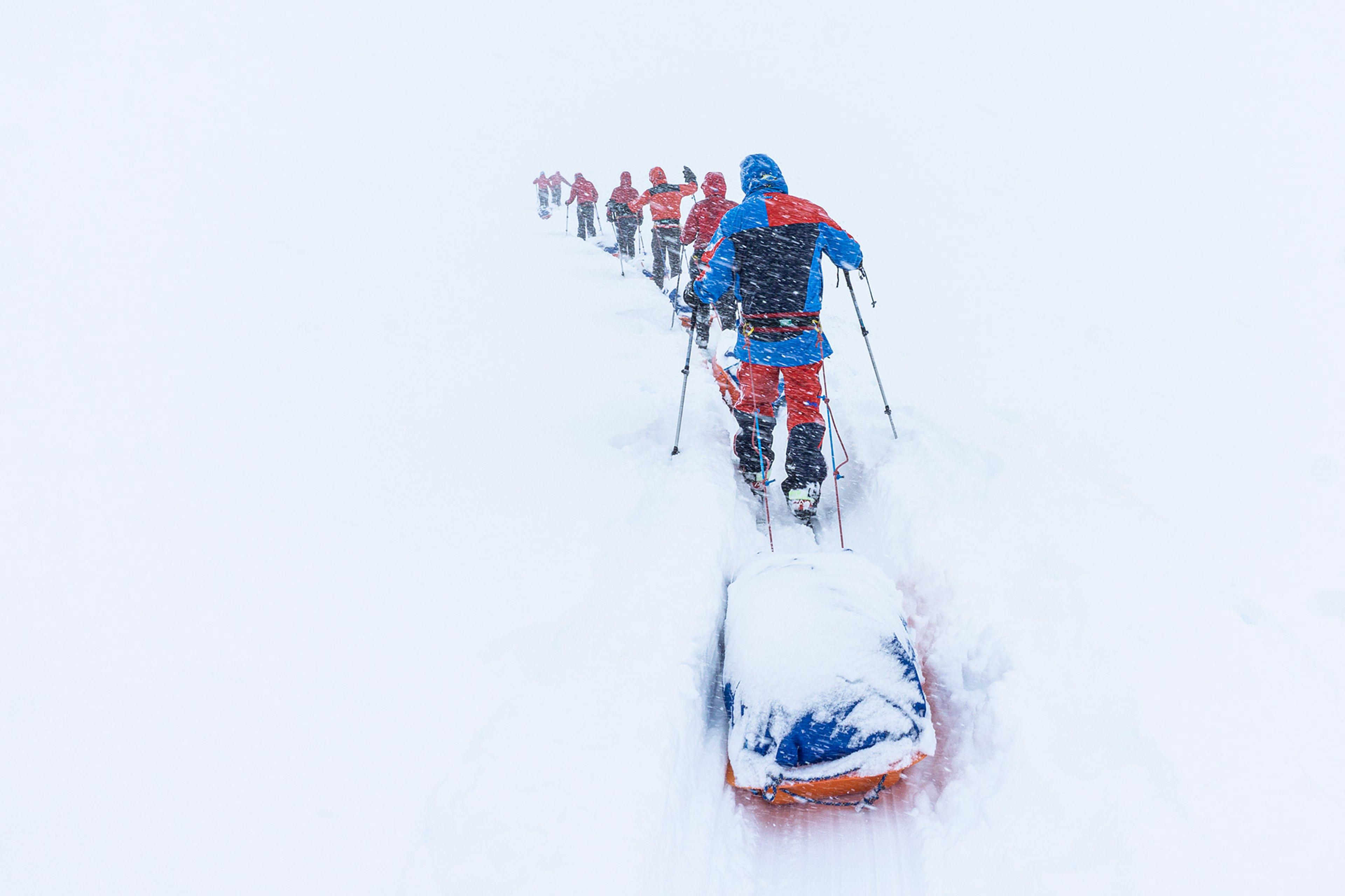 Group of skiers hauling pulkas in bad cisibility on the ice