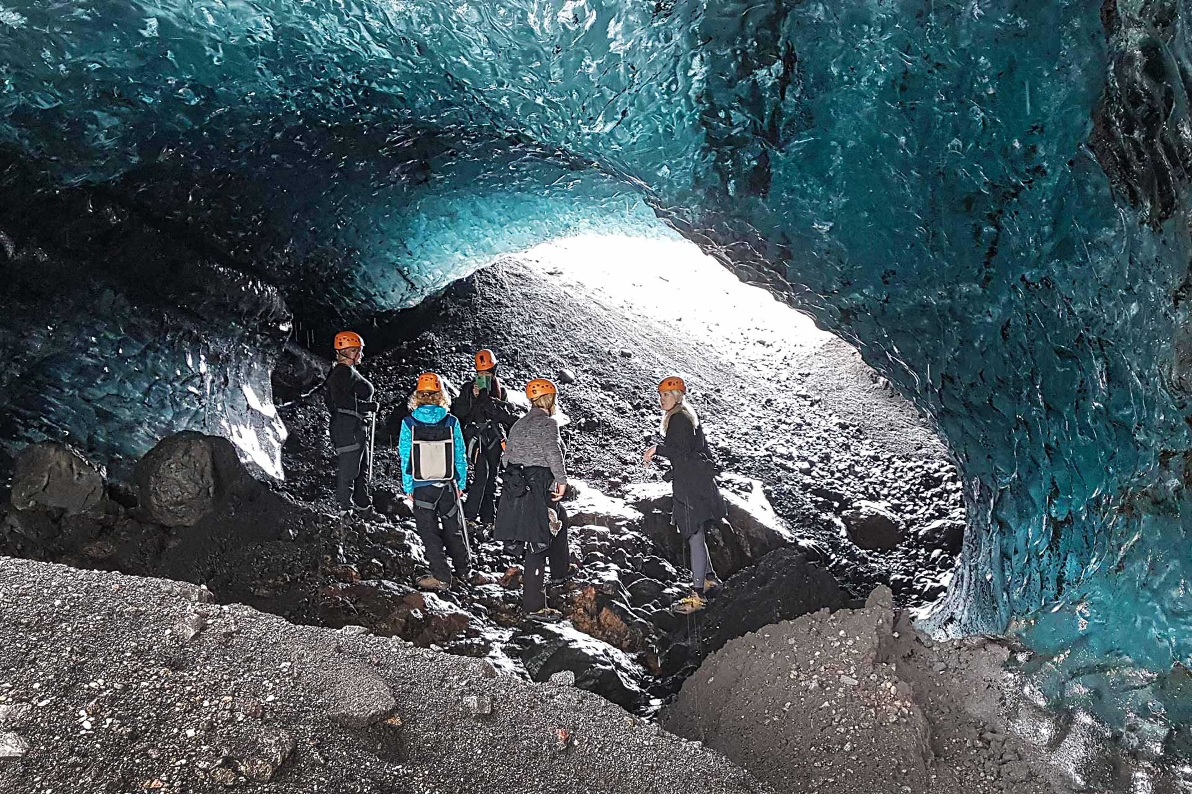 A group of people inside a very blue ice cave in a glacier