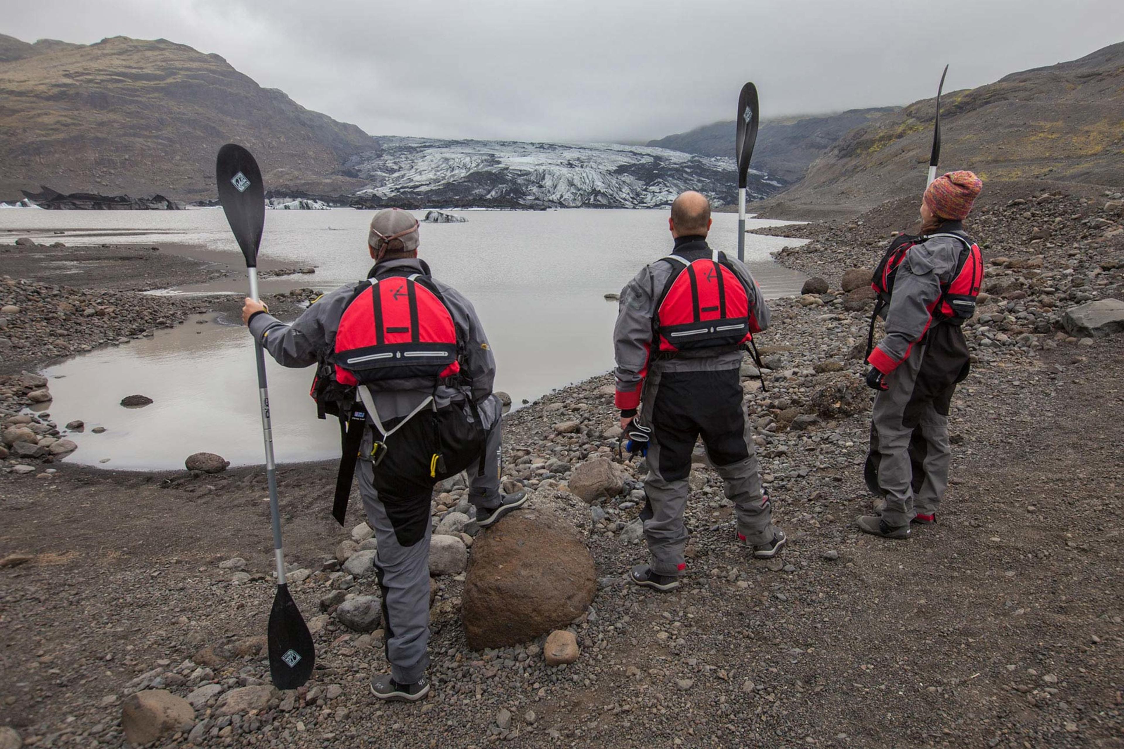 Three persons holding ores looking at the glavier lagoon before a kayak tour