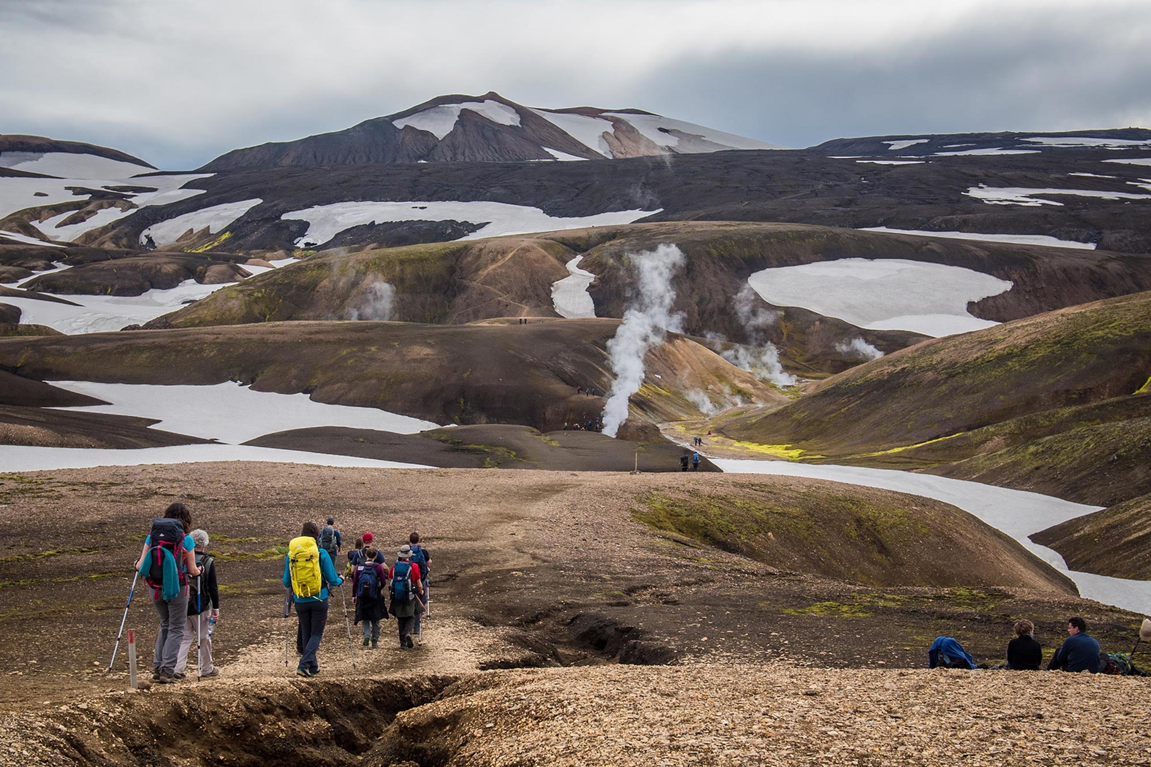 People hiking toward mountains wih snow on the Laugavegur trail.