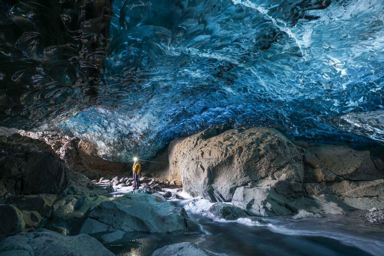 A cave in Iceland with a blue ice ceiling and a river inside
