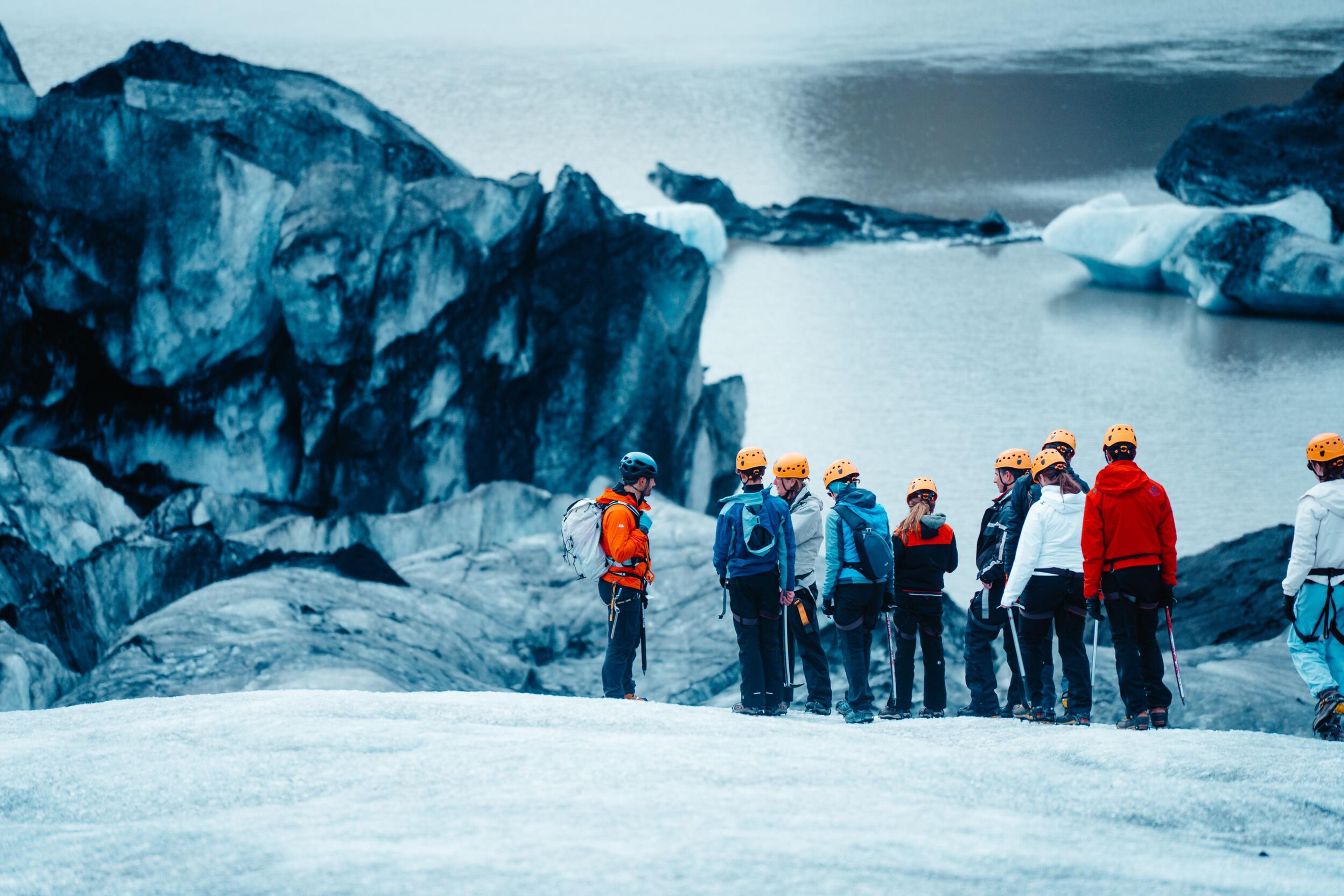 A group of travelers stood on a glacier with a glacier lagoon in the bacground