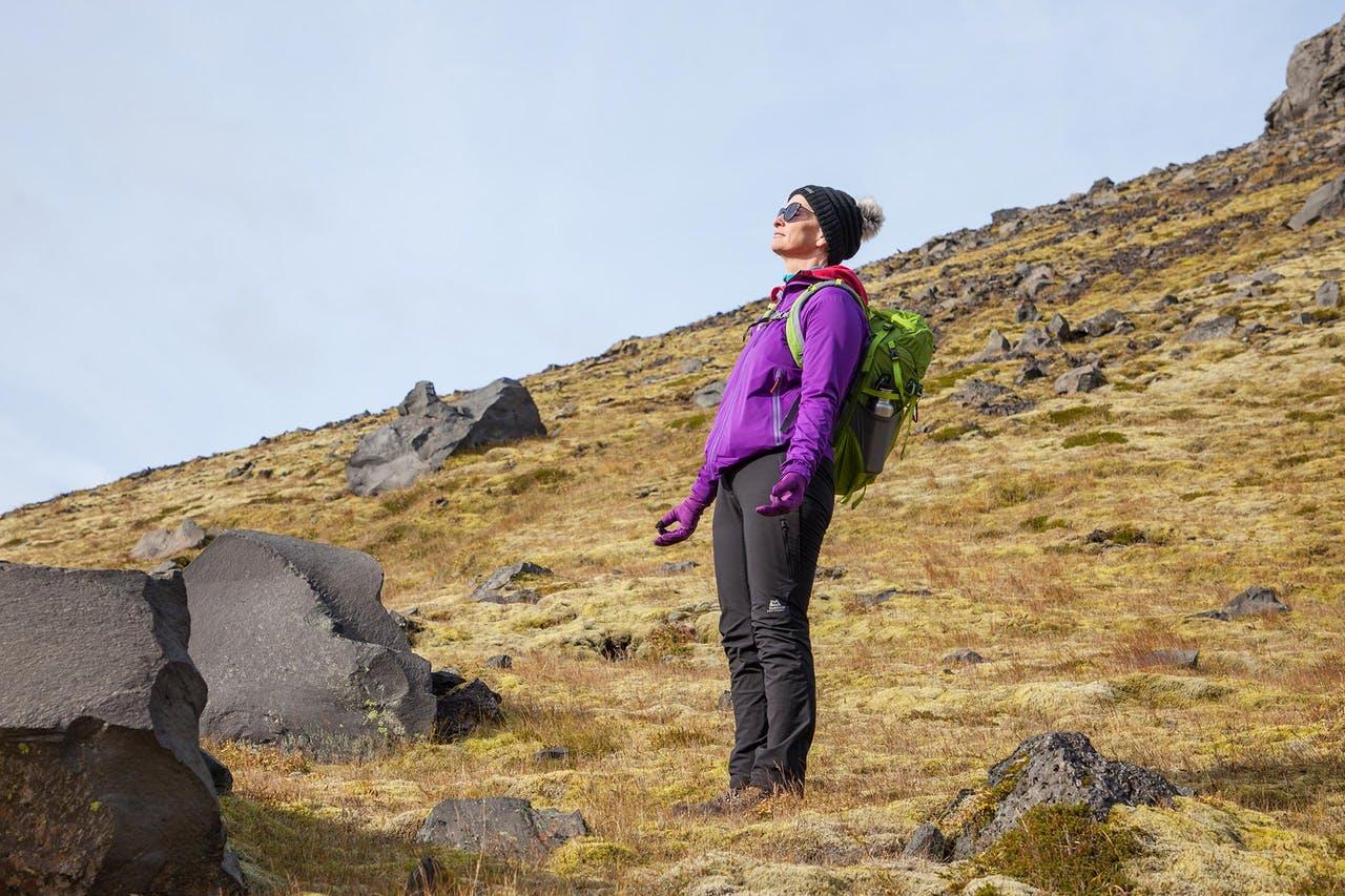 Woman in a purple jacket enjoying the sunlight on her face during a hiking tour in Iceland in May