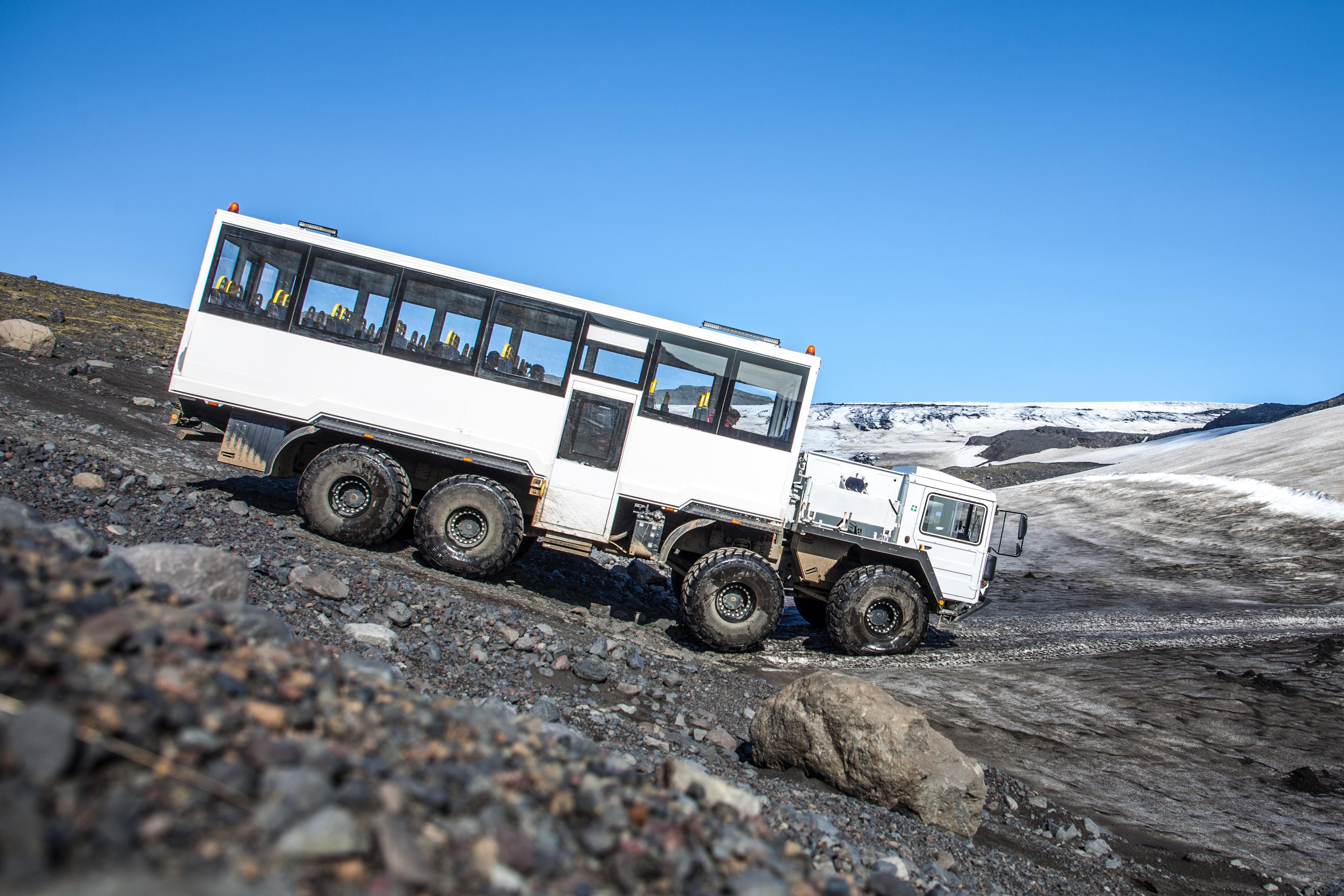 The awesome glacier monster truck moving a long the gravel road that leads up to the glacier