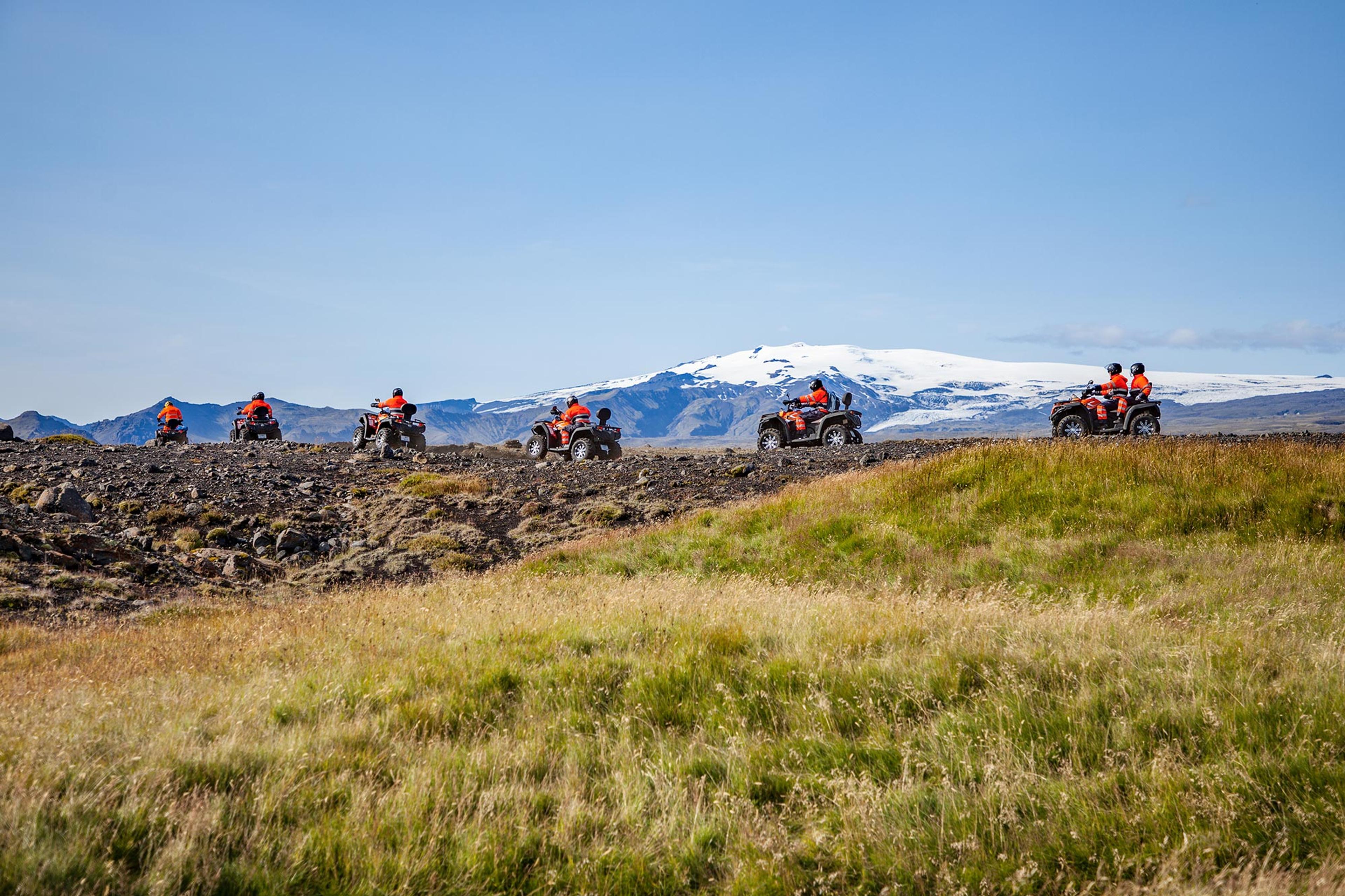 Riding by a grassy spot on the otherwise black sandy terrain of Sólheimasandur area