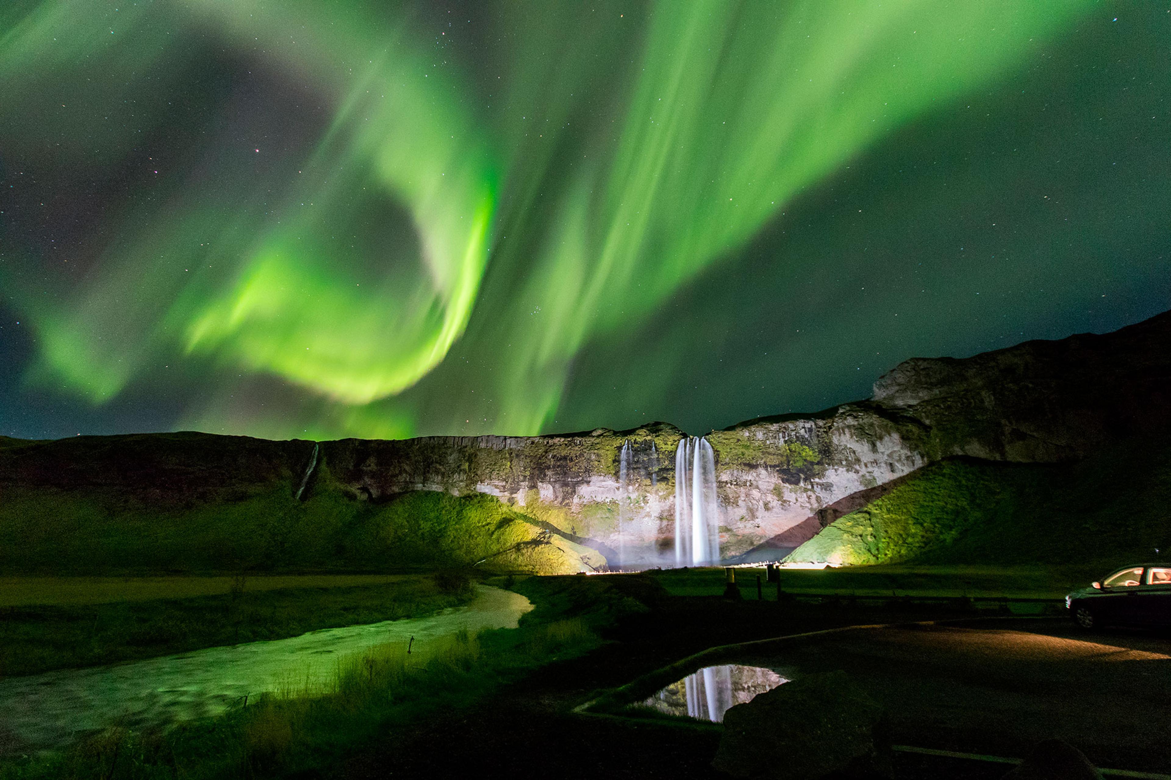 Green aurora borealis over Seljalandfoss waterfall. Winter is the best time to visit Iceland to see Northern Lights