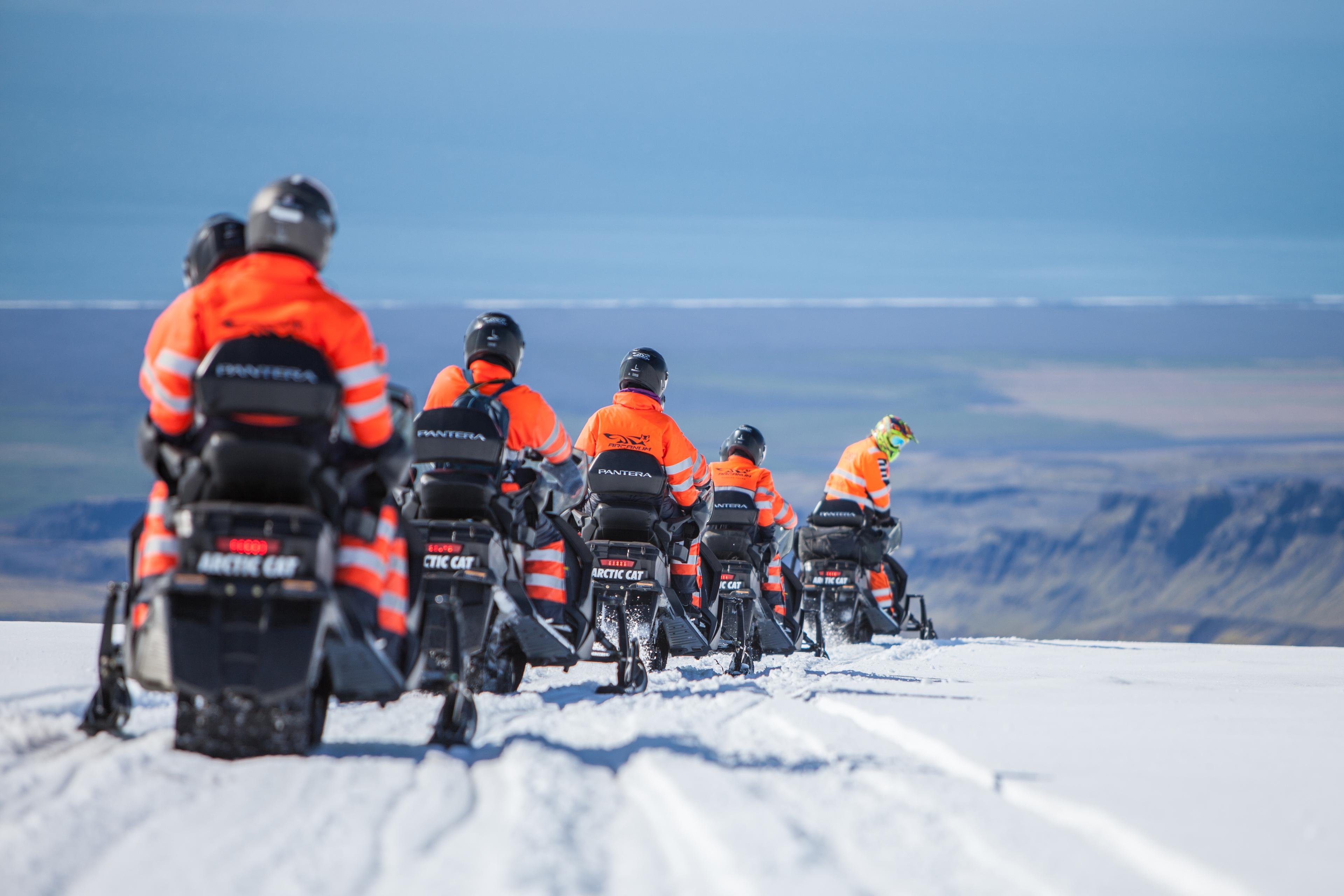 Back view of a group of snow scooter drivers but the guide is looking back to see if everything is ok