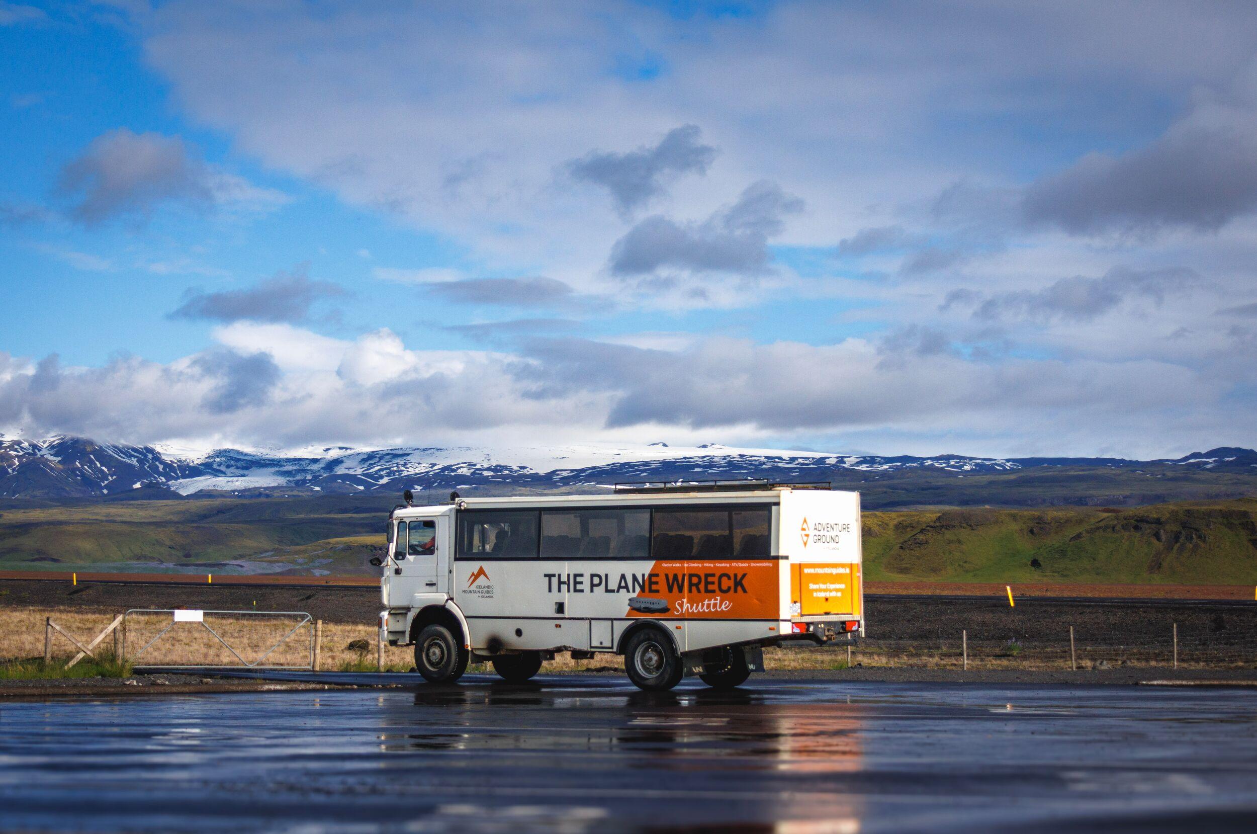 bus driving through black sand dessert looking nature under blue sky