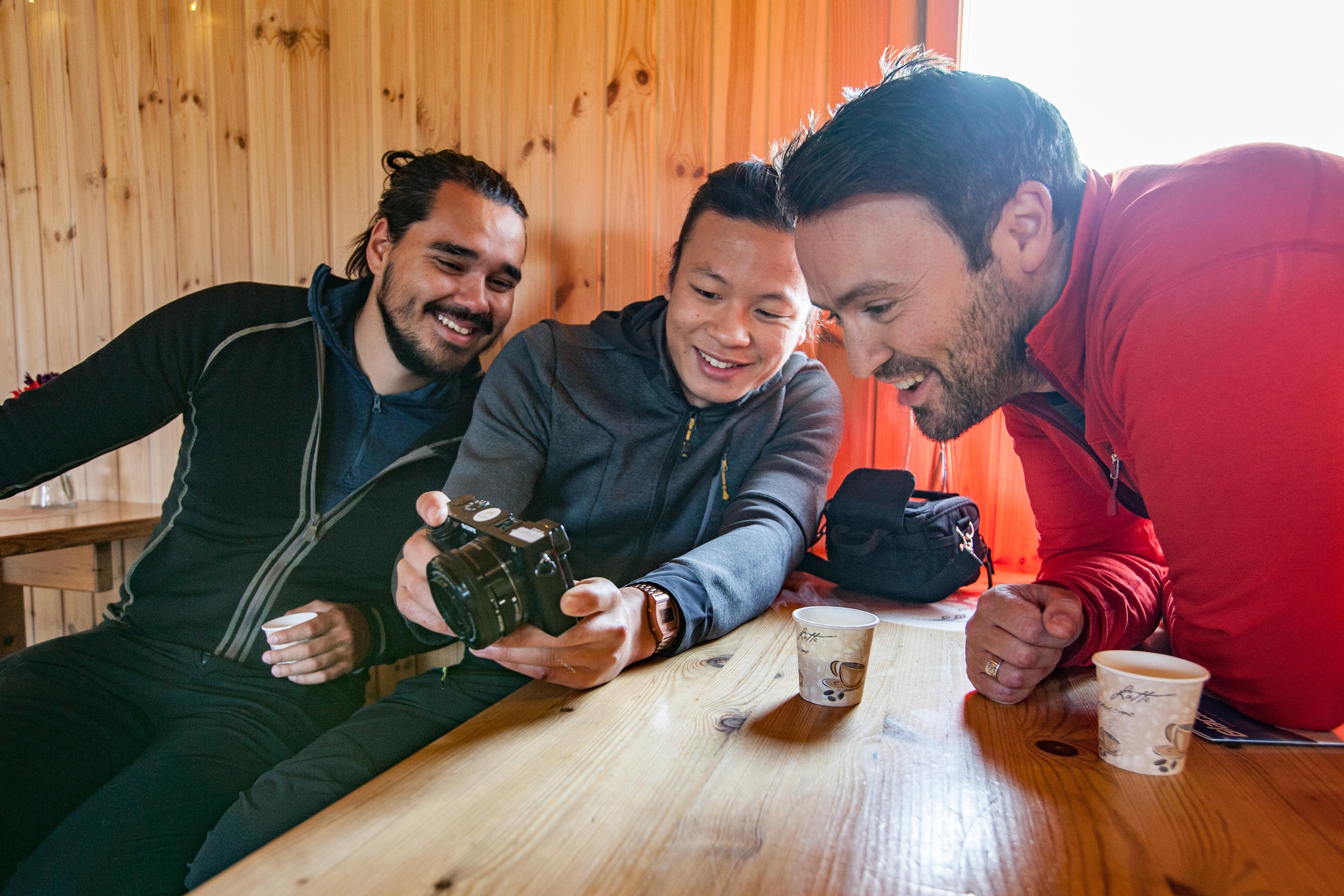 Three guys looking at photos in a camera after the tour