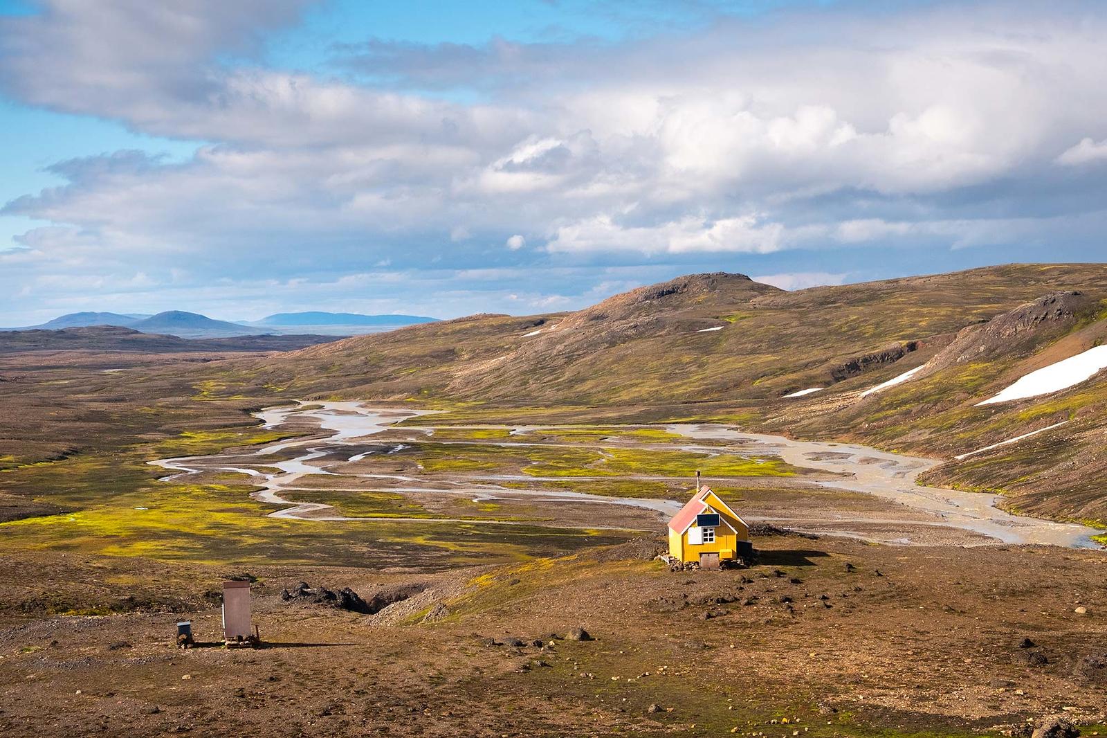 A mountain hut in magnificent landscape and river flowing by