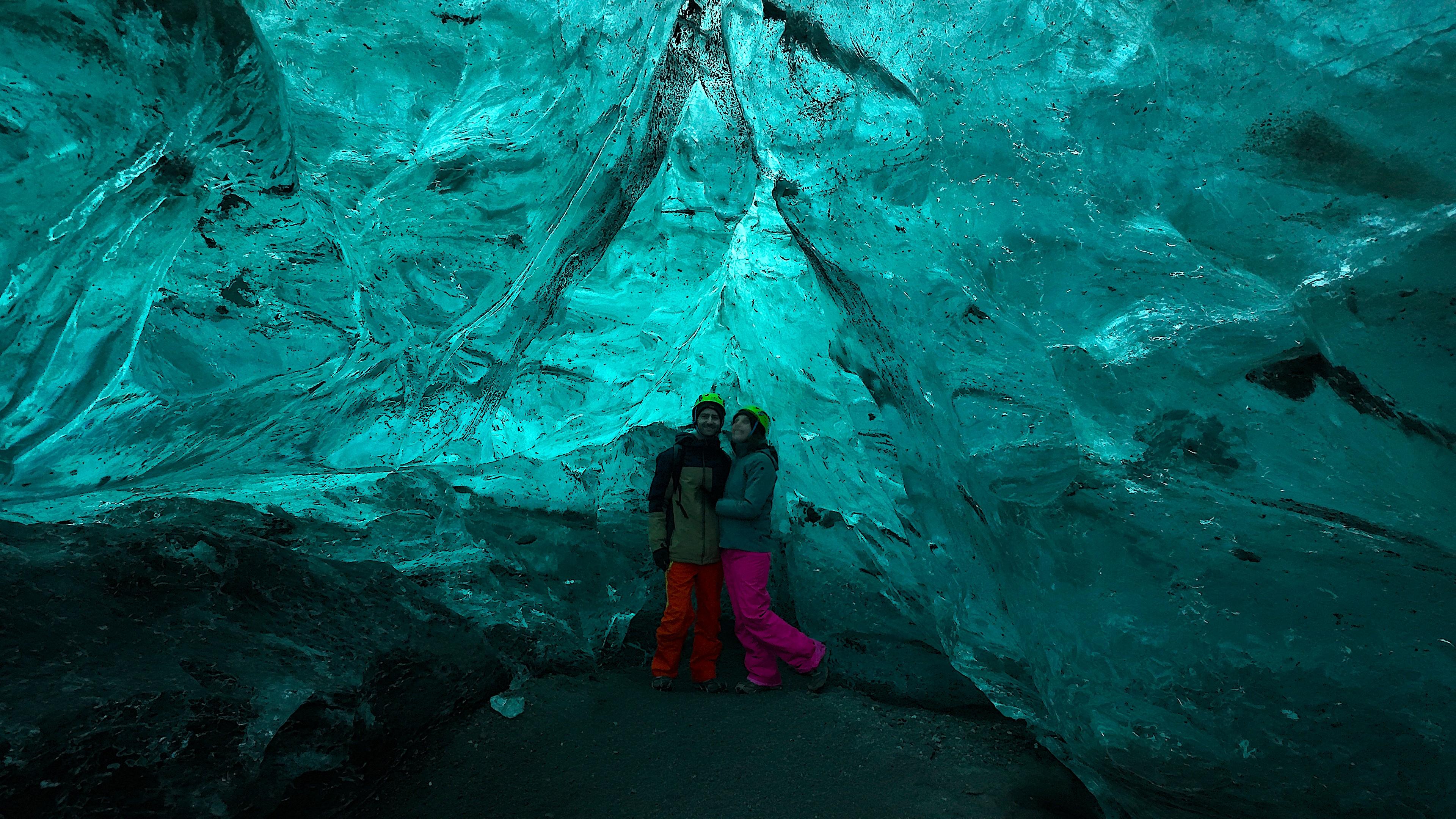 A smiling couple standing in an ice cave