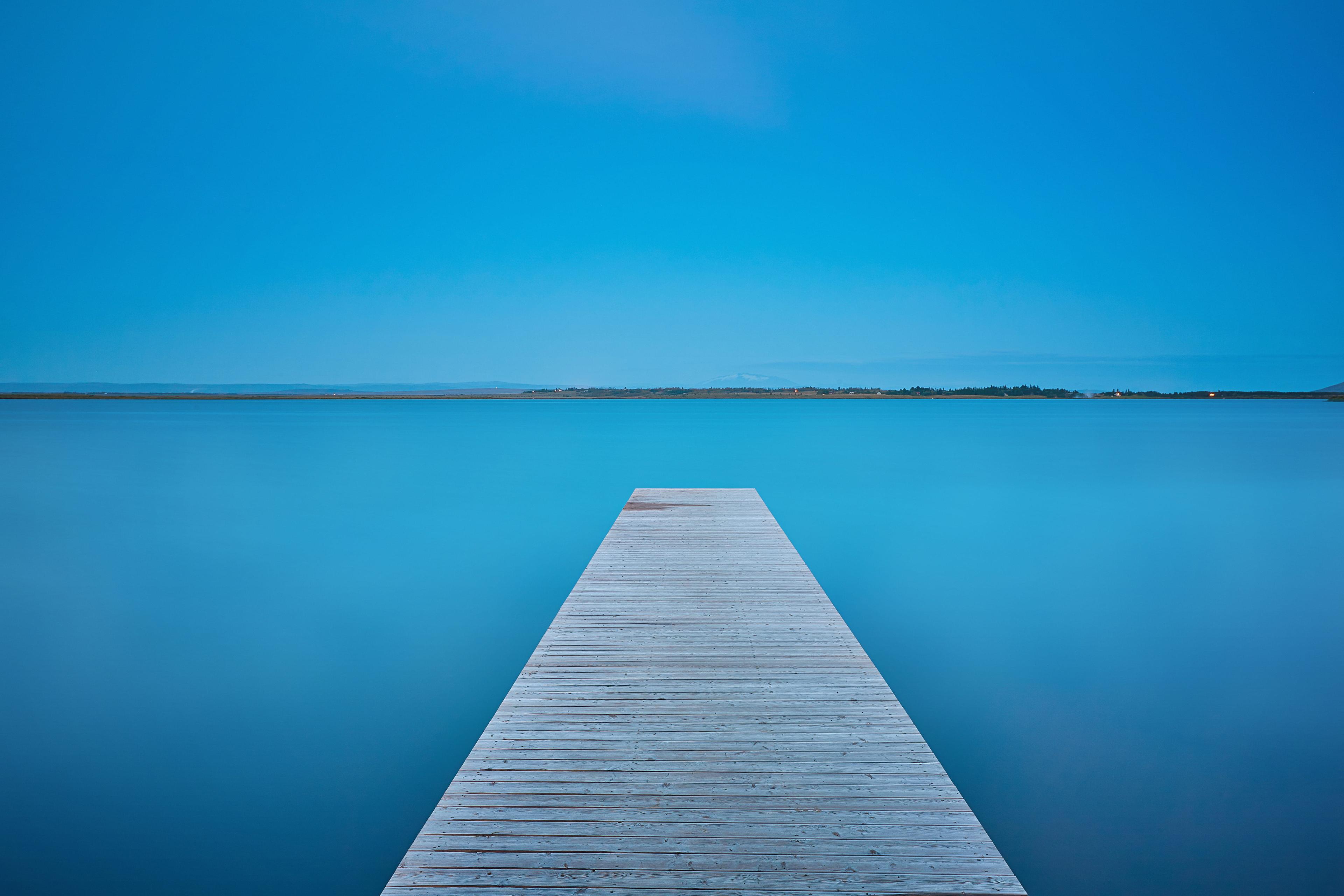 A wooden pier on the Laugarvatn lake with blue skies above.