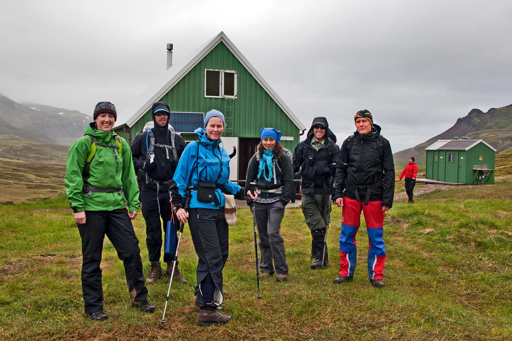 Hikers posing in front of a green hut on a cloudy day in the east fjords in Iceland