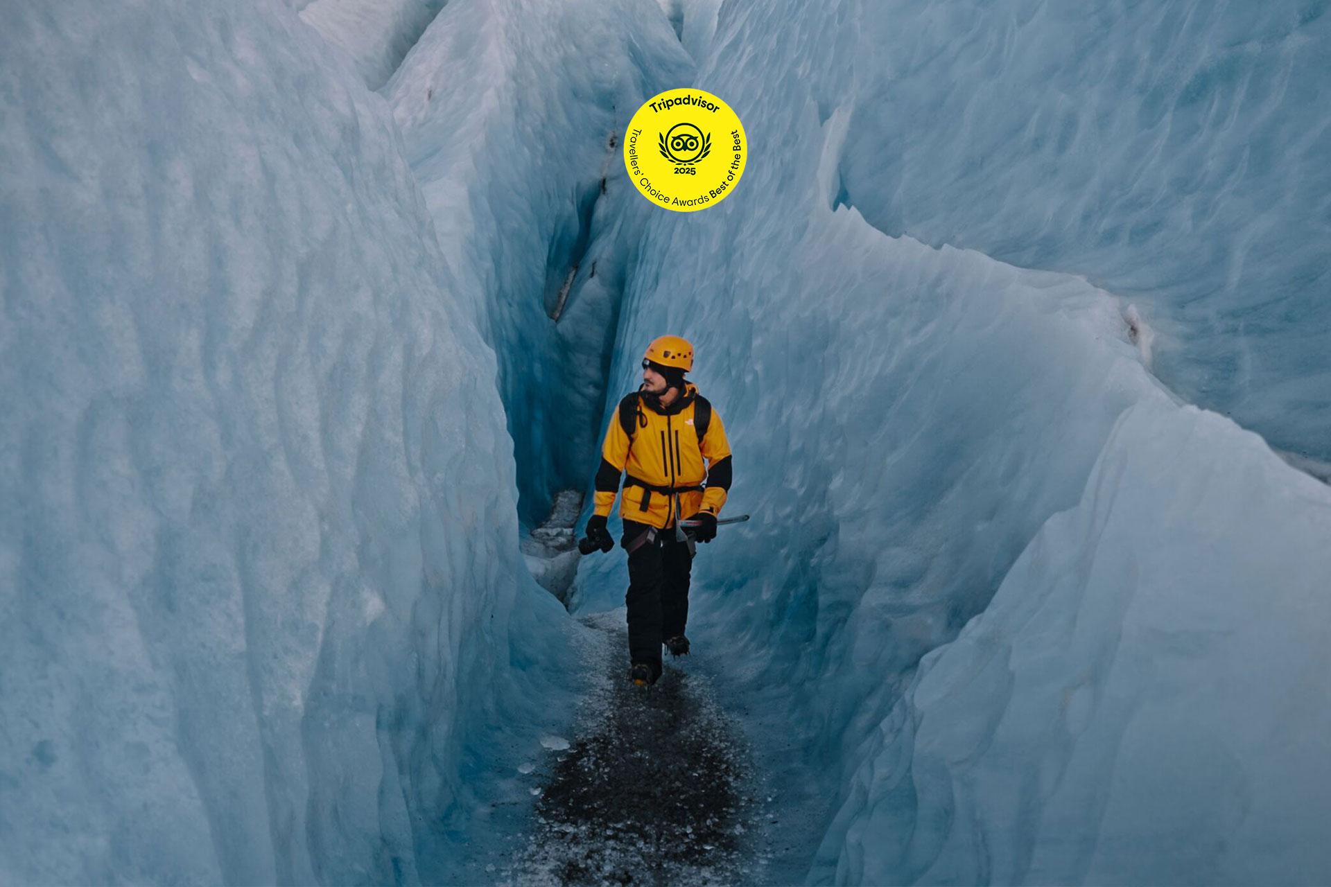 A lone hiker walks among blue ice walls on the Vatnajökull glacier.
