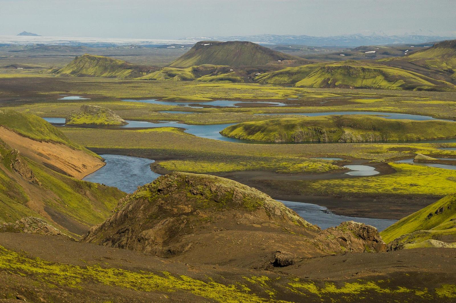 A small hilly valley covered in moss with rivers running through it