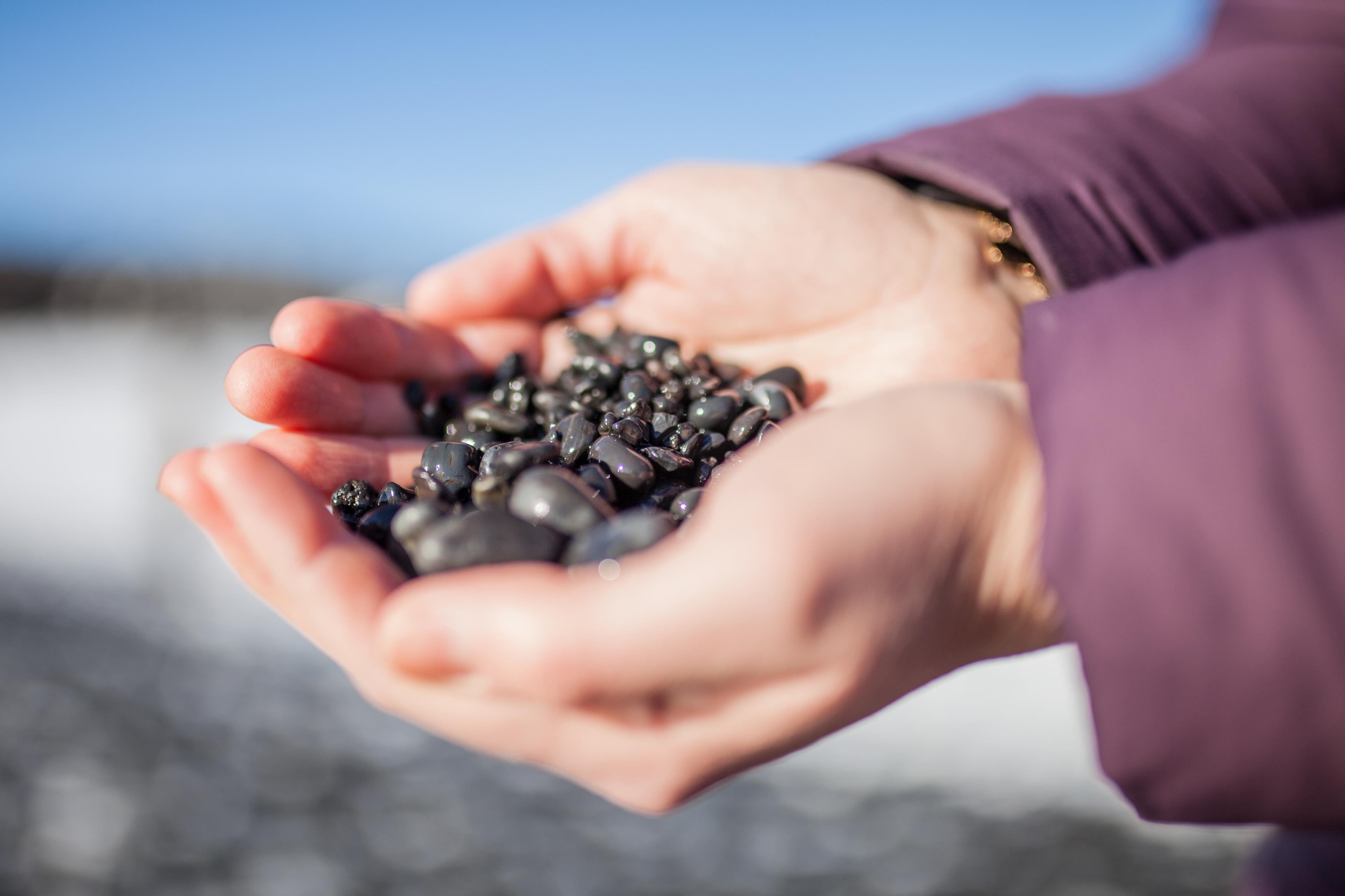 Hands holding pebbles on the beach