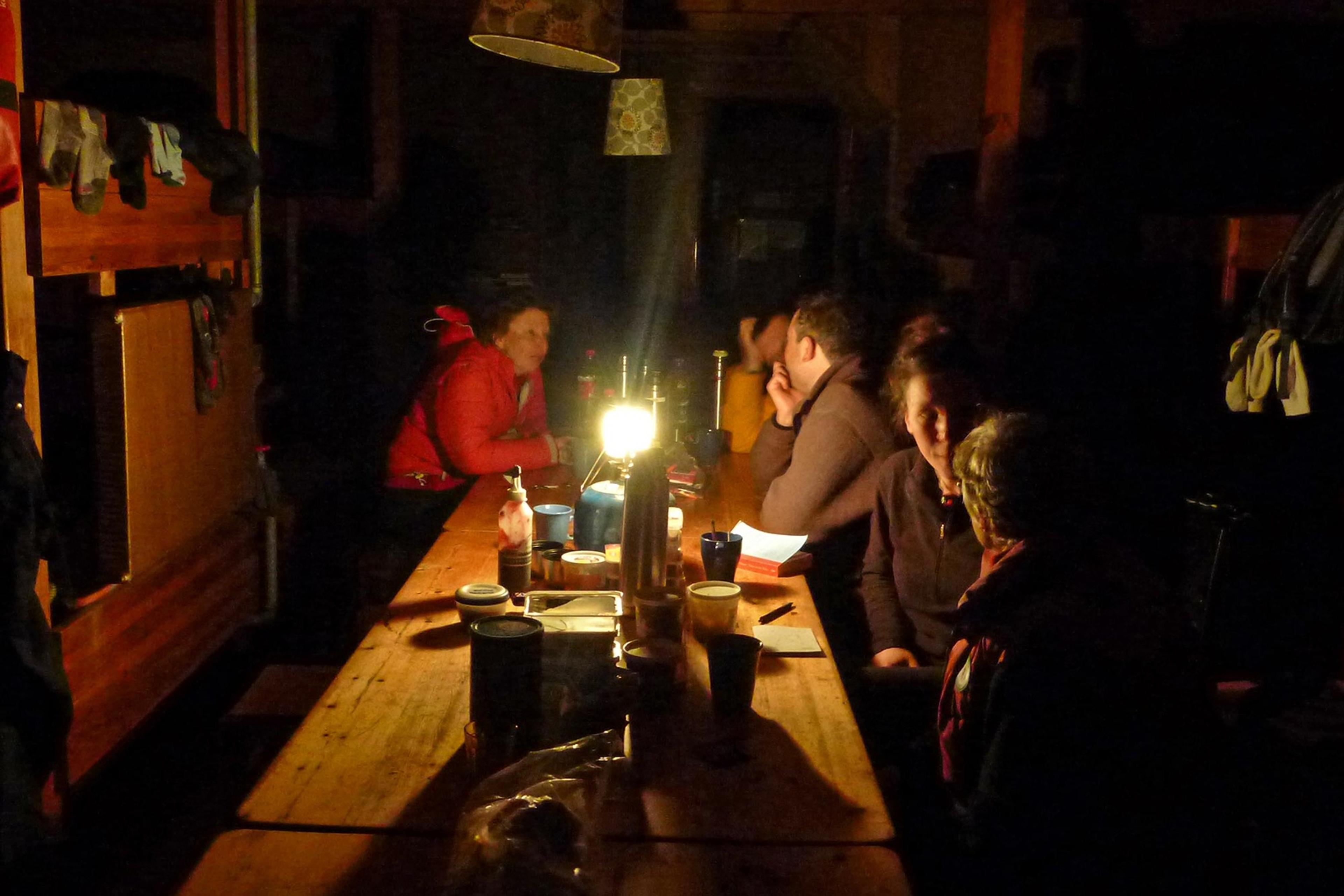 People sitting by a little light on the table inside an old hut in the highlands