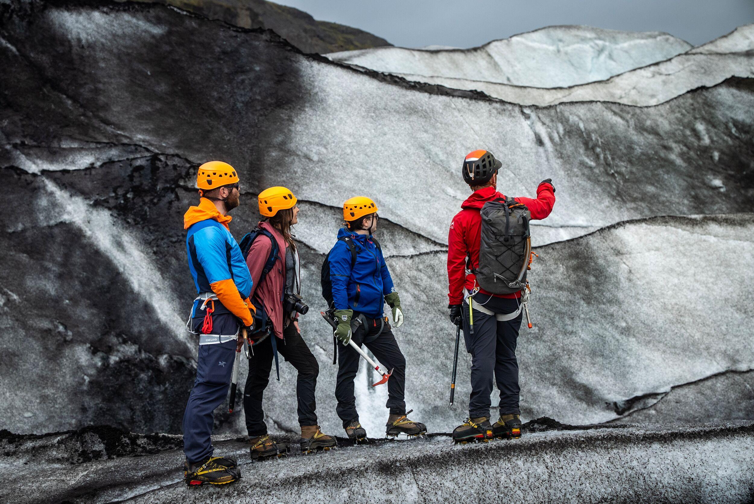 A guide and three hikers on the ash-streaked Sólheimajökull glacier in Iceland