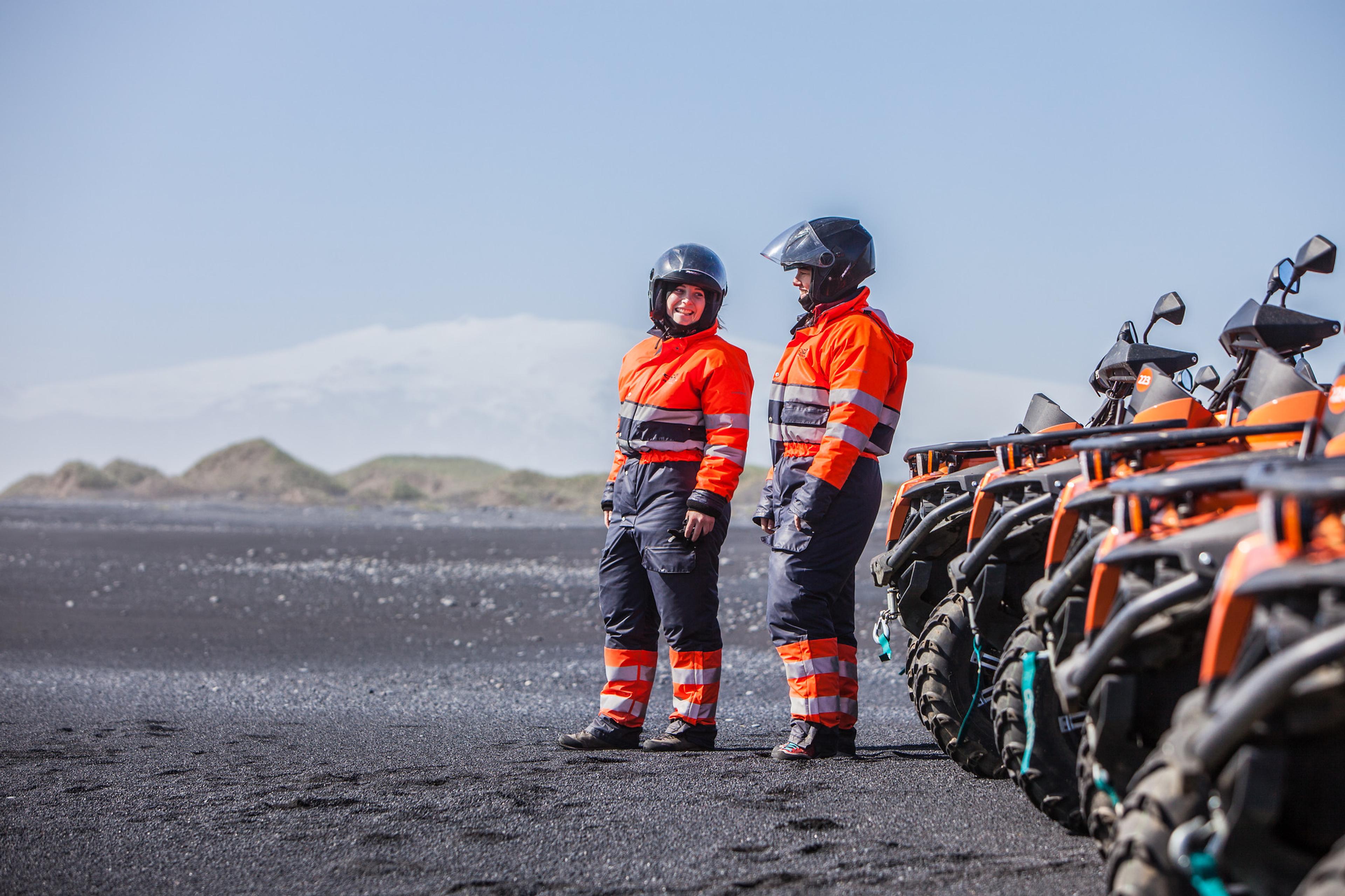 Two girls standing in front of their ATV quad bikes near the ocean