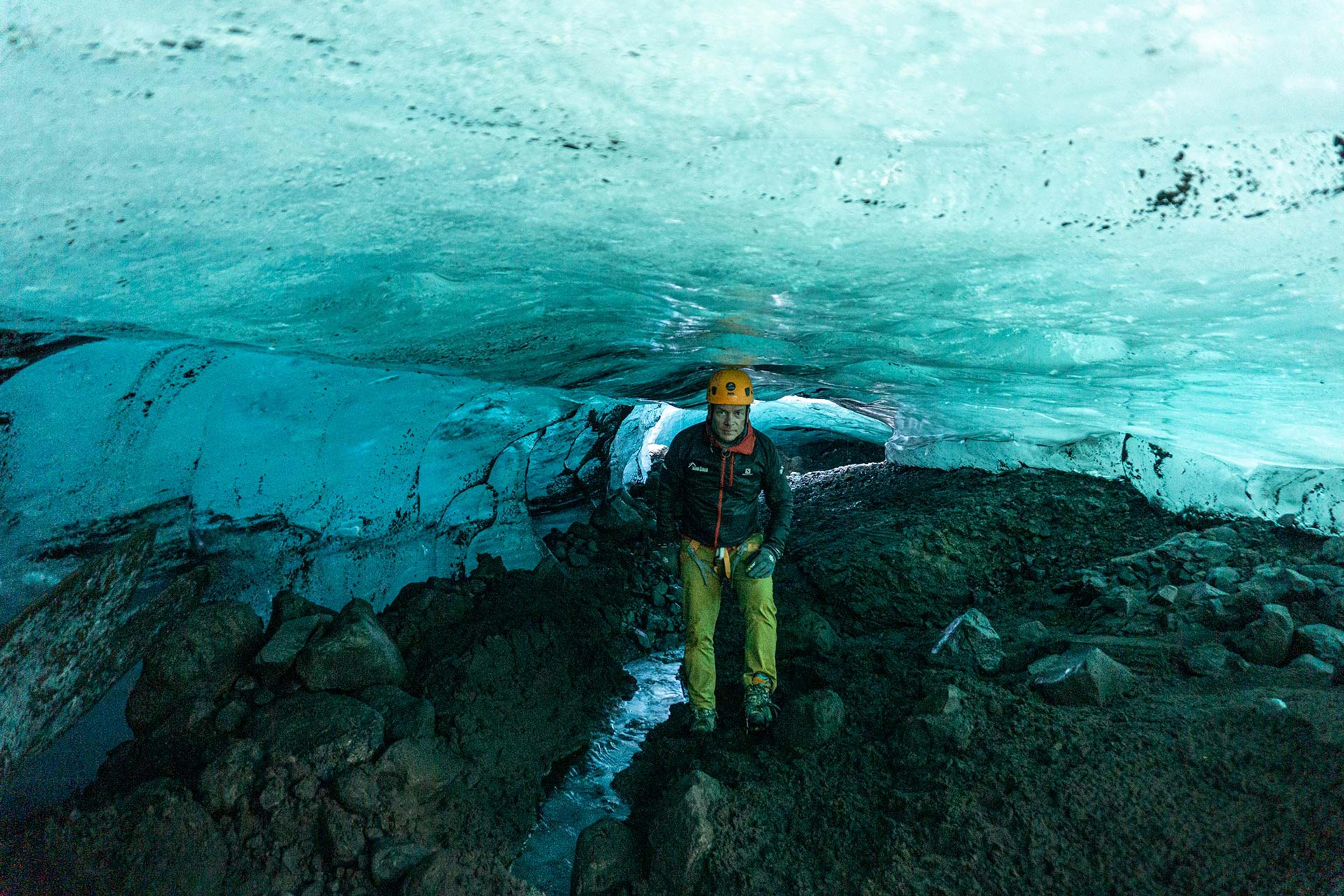 A man standing inside a blue ice cave in Sólheimajökull