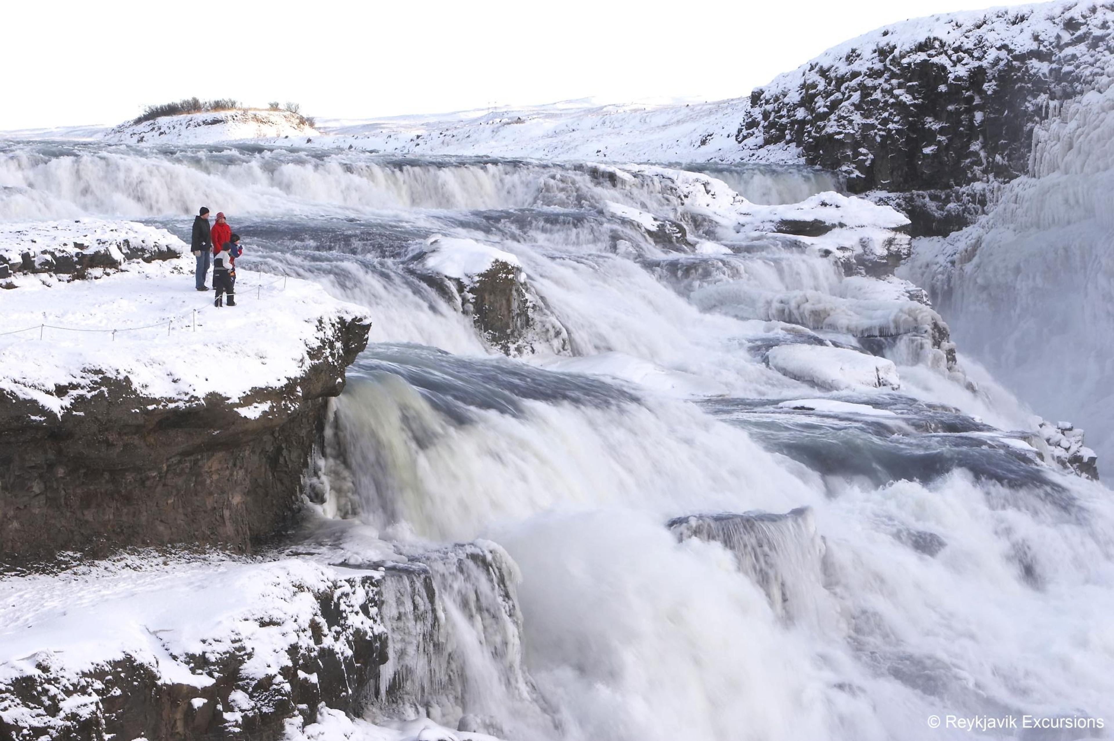 A couple standing next to Gullfoss waterfall in winter