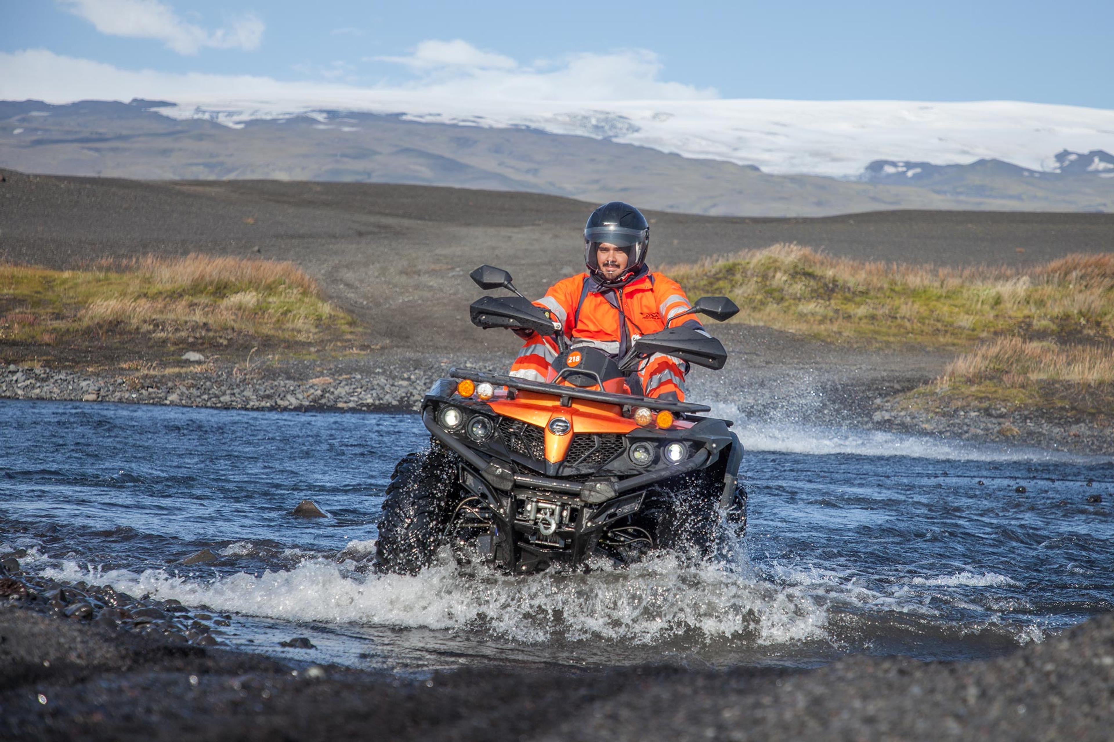 An man crossing a river and the glacier in the background