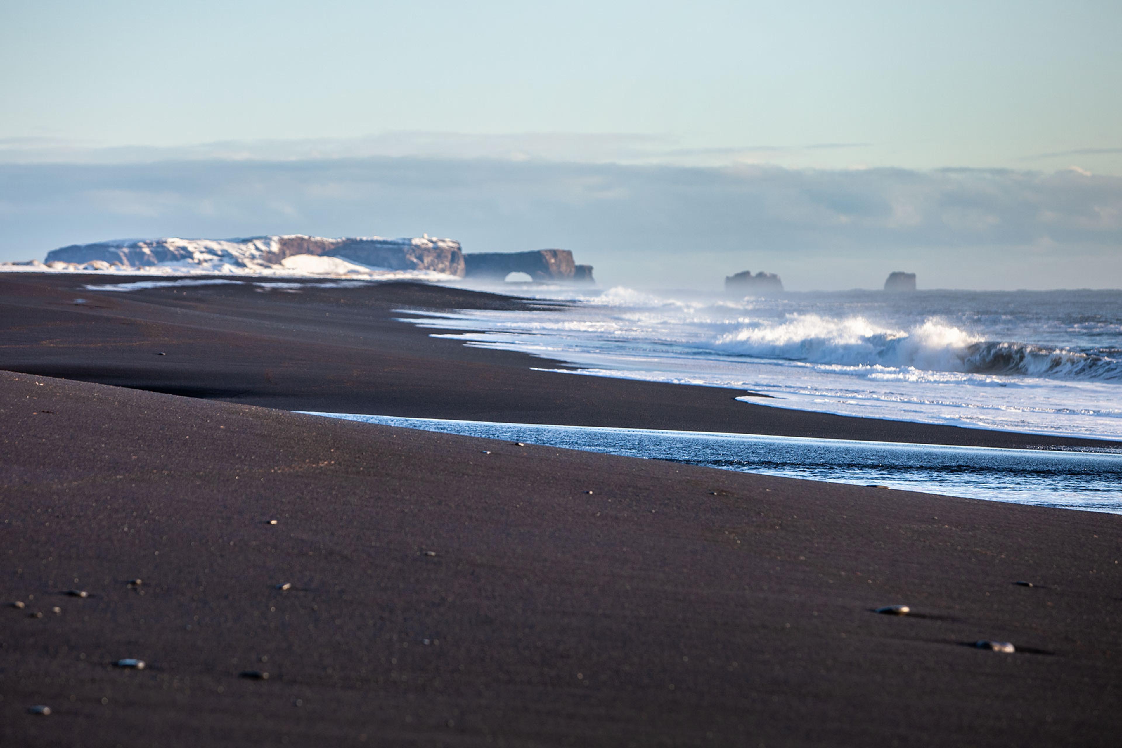 black sand beach and mountains in the back round 