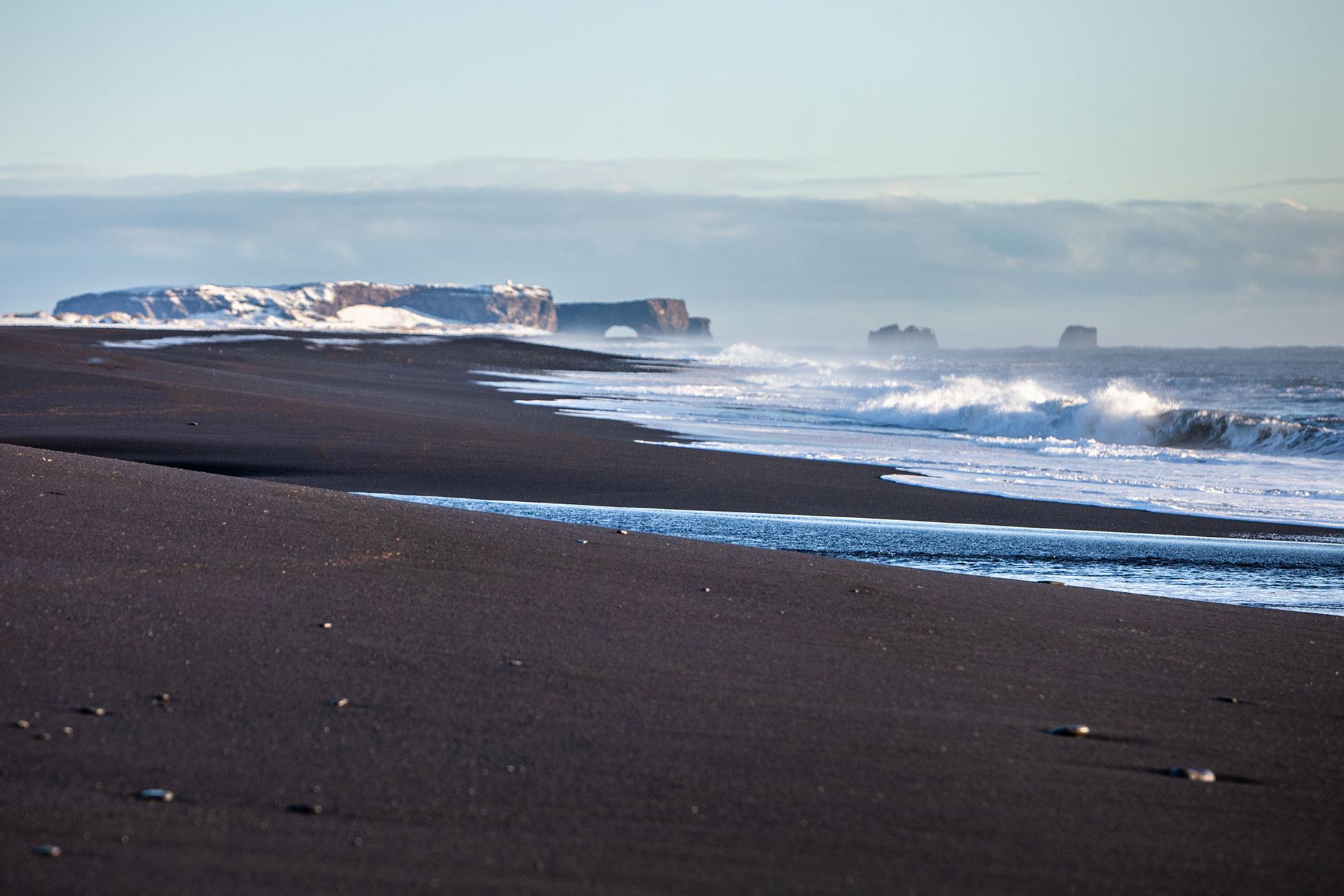 black sand beach and mountains in the back round