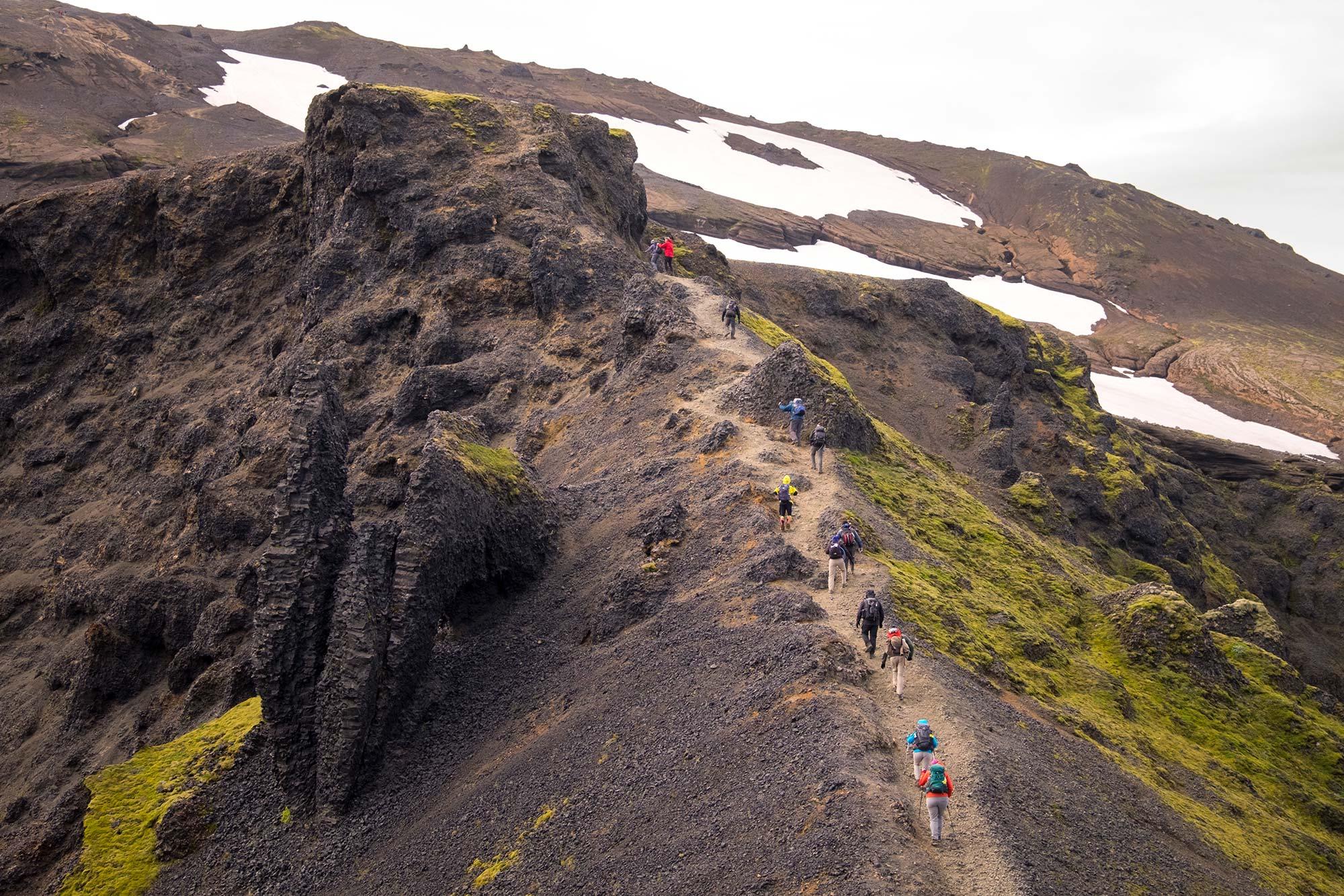 A group of people with a guide walking on a sandy path on Fimmvörðuháls