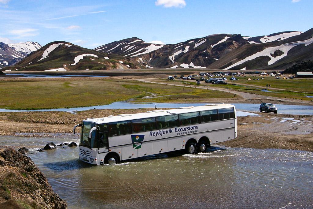 A large modified bus crosses the river at landmannalaugar