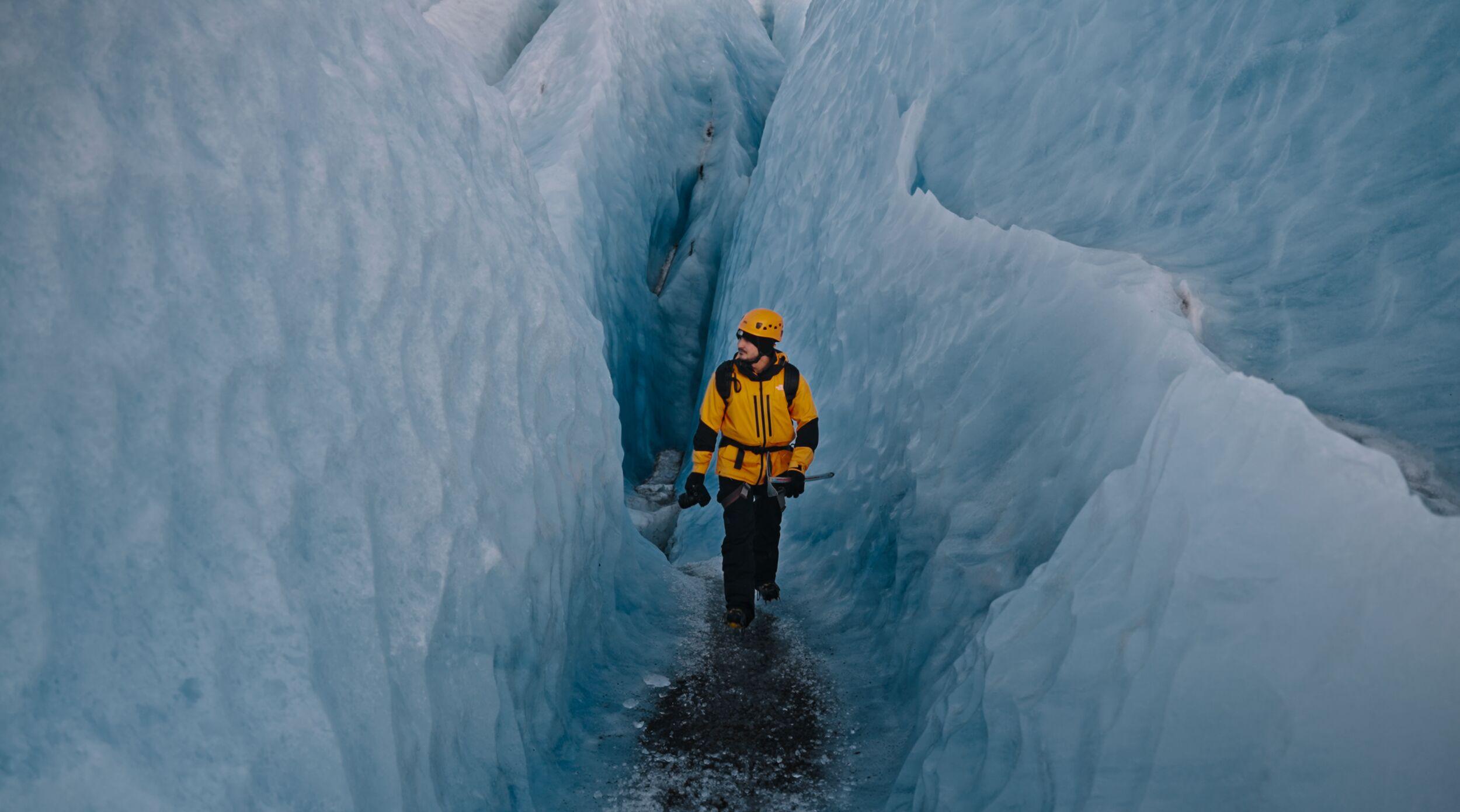 A lone hiker walks among blue ice walls on the Vatnajökull glacier.