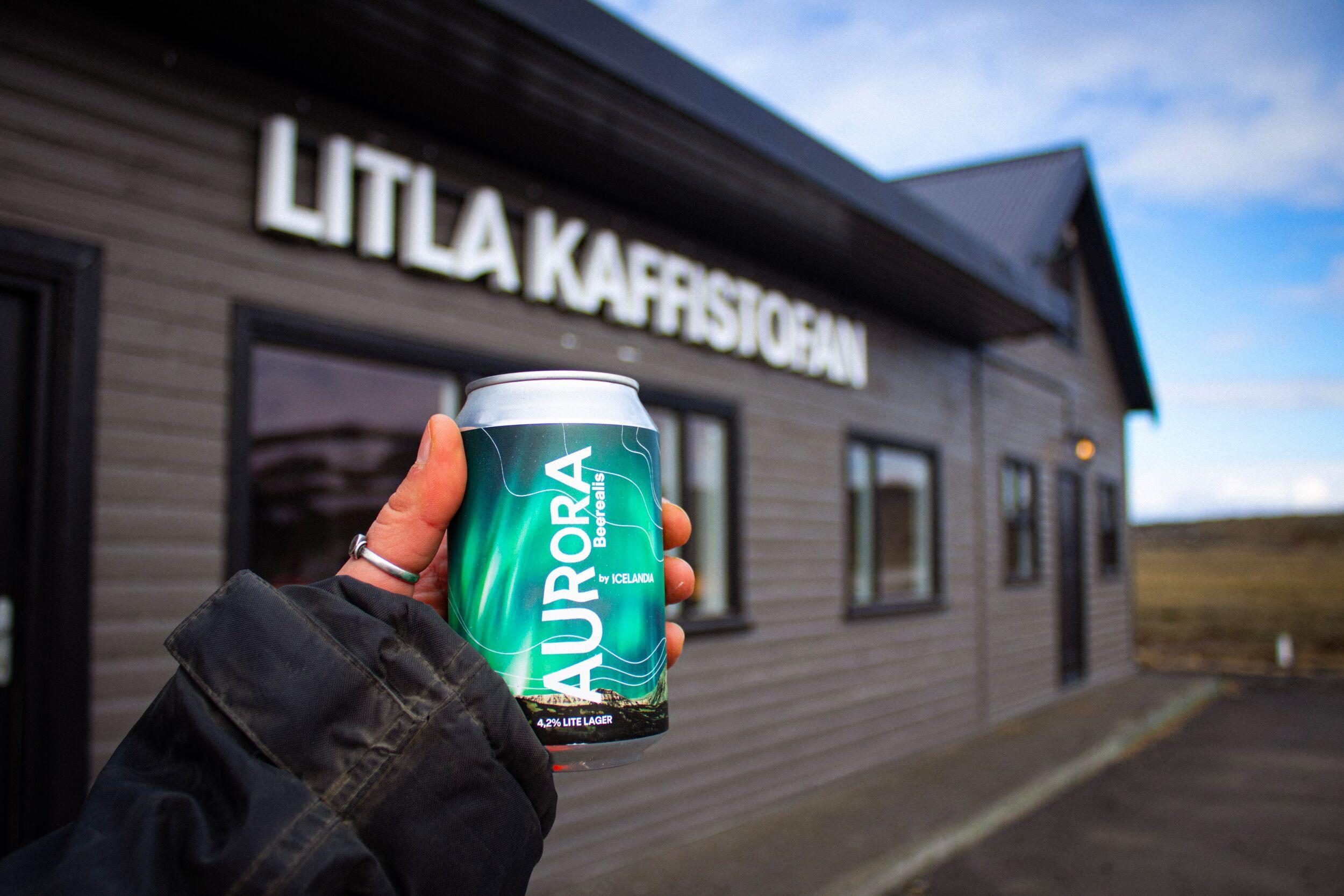 hand holding a can called aurora in front of Litla Kaffistofan