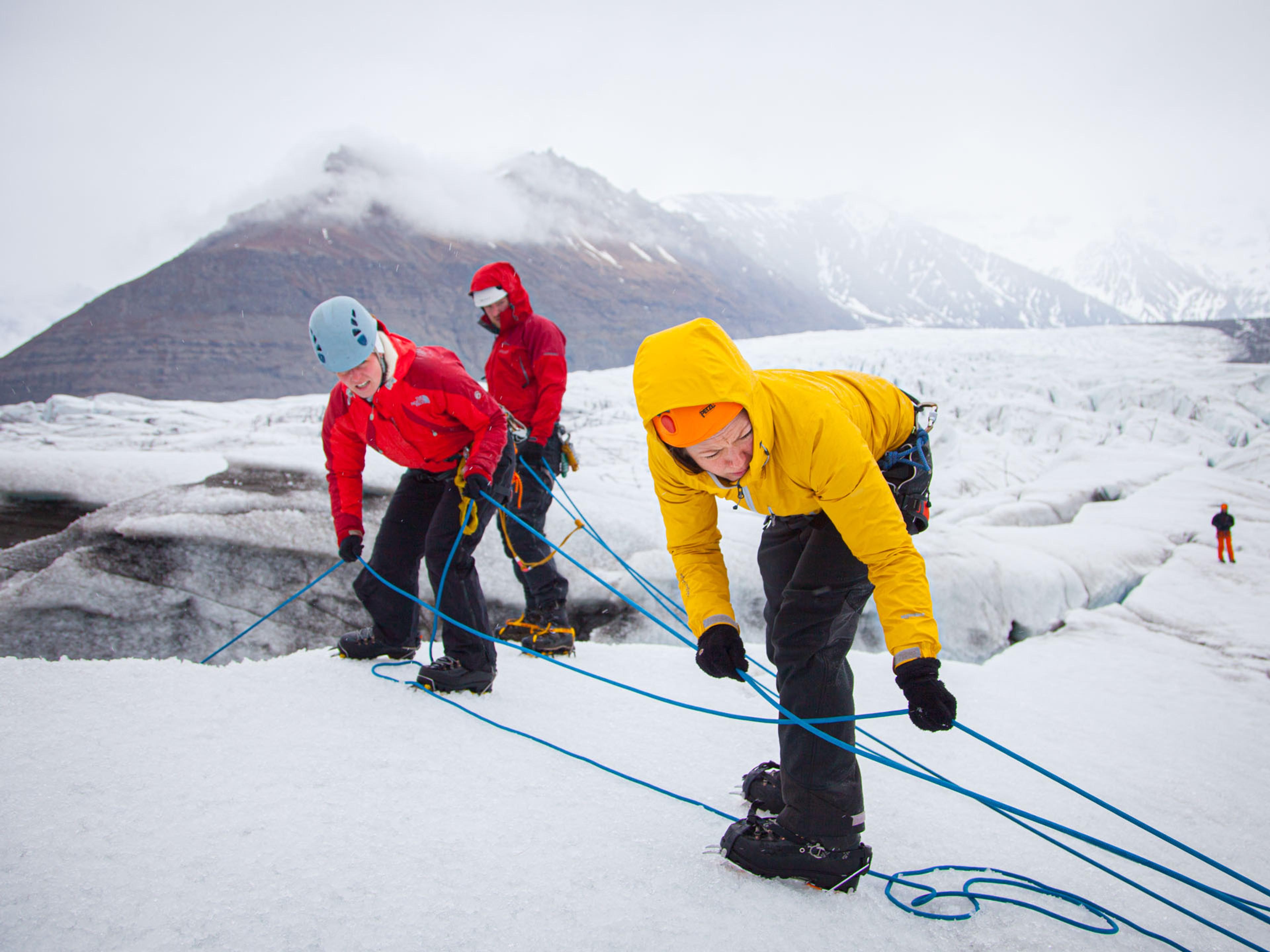 A group of people securing the ropes before Ice climbing in the cold