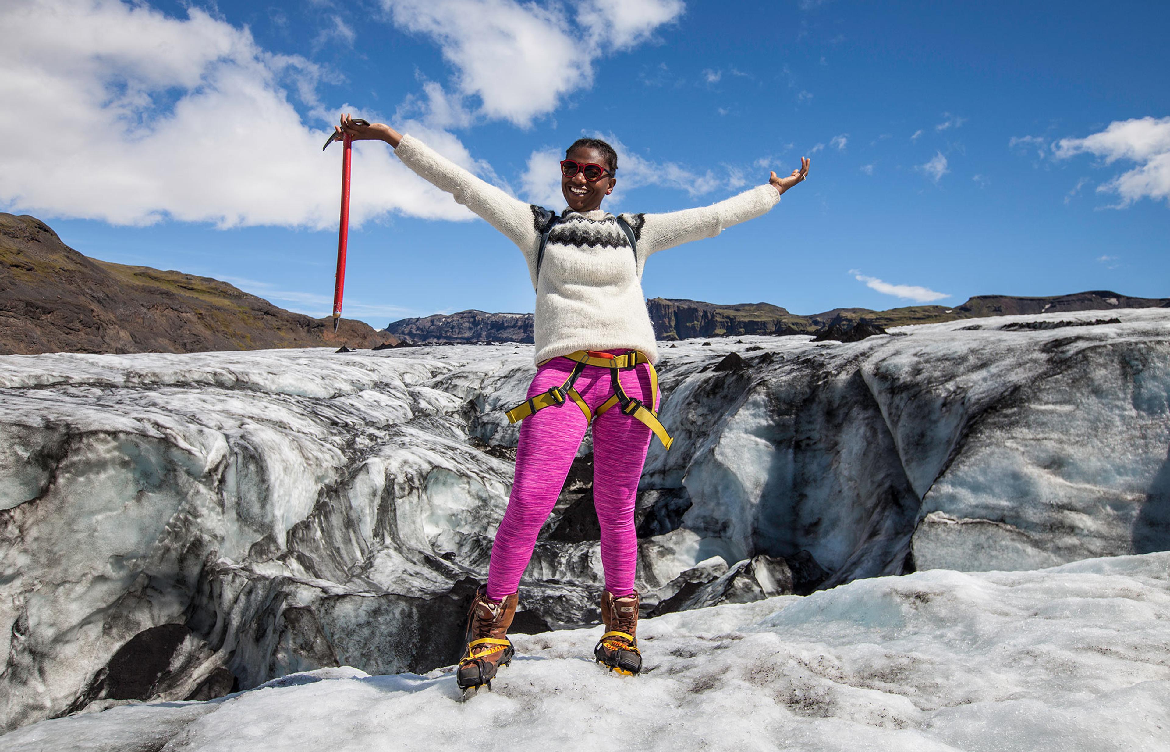 A woman standing on top of Solheimajokull glacier with an ice axe in her hand.