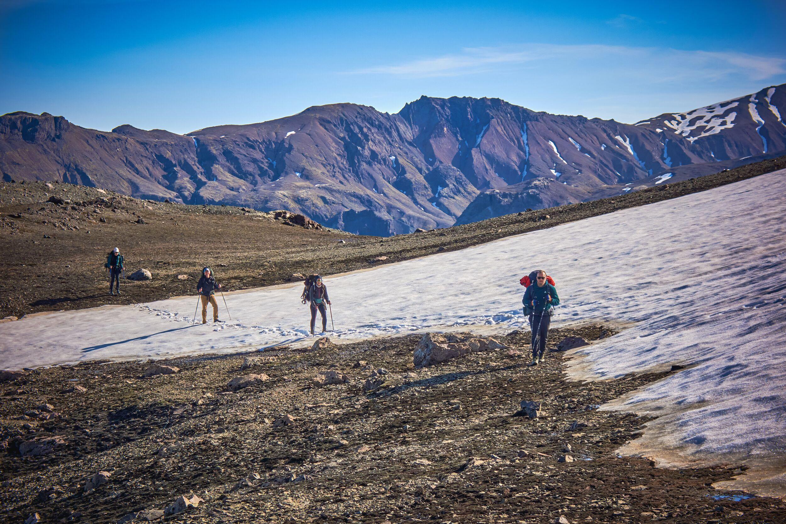 Four people hiking by a glacier