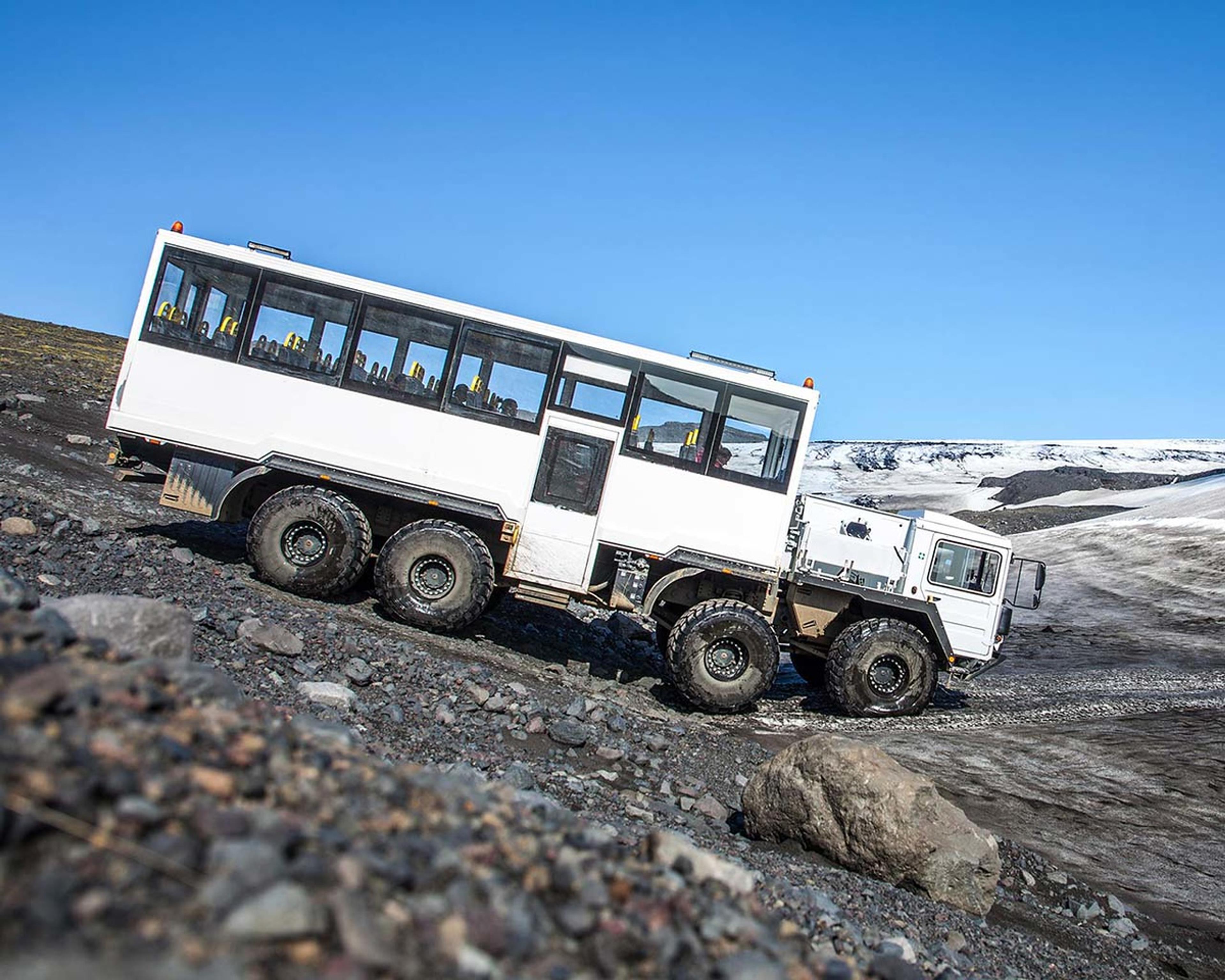 Huge glacier truck takes people up towards where the snow scooters are parked