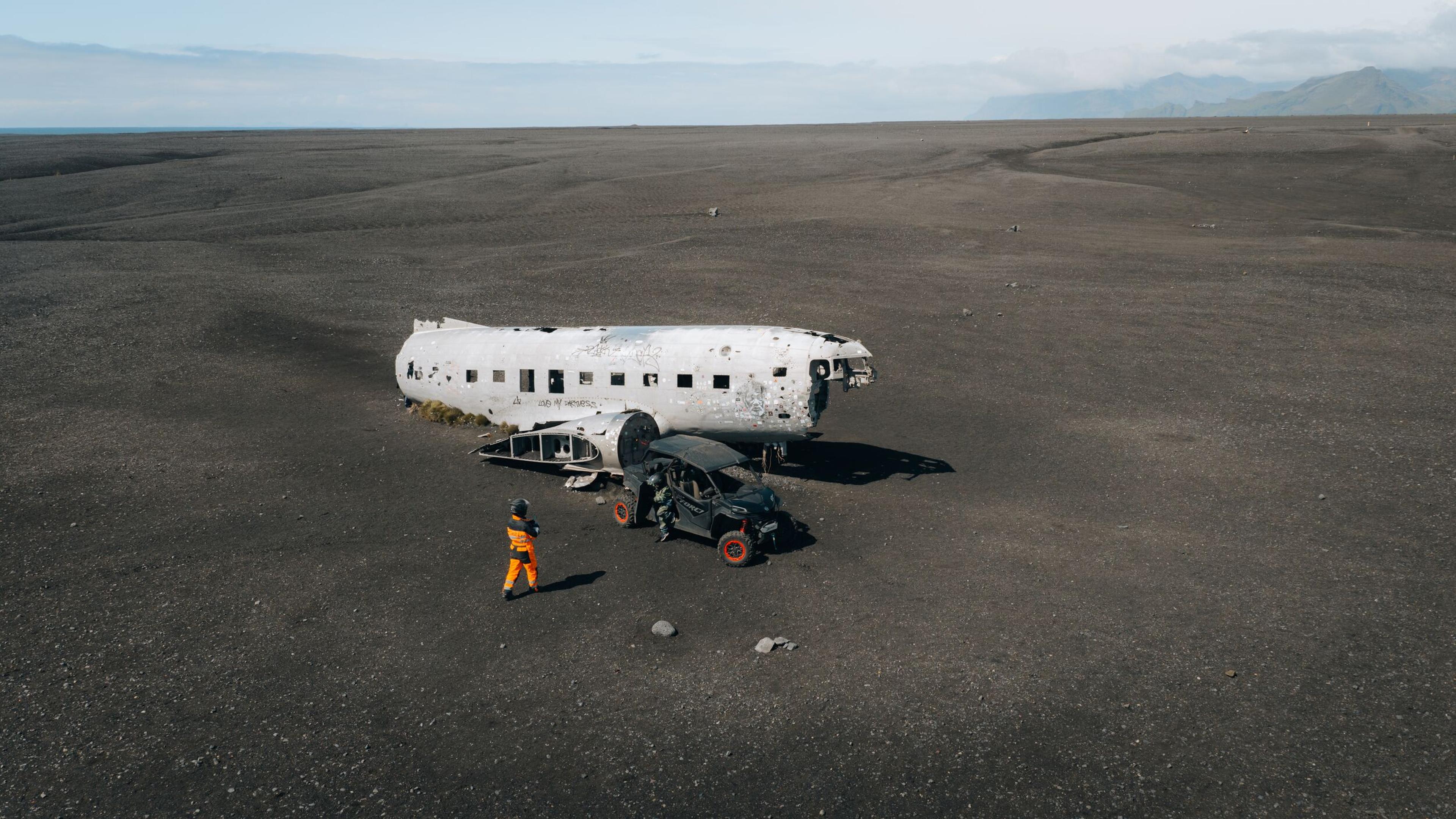 four people standing on a black sand beach in front of a buggy