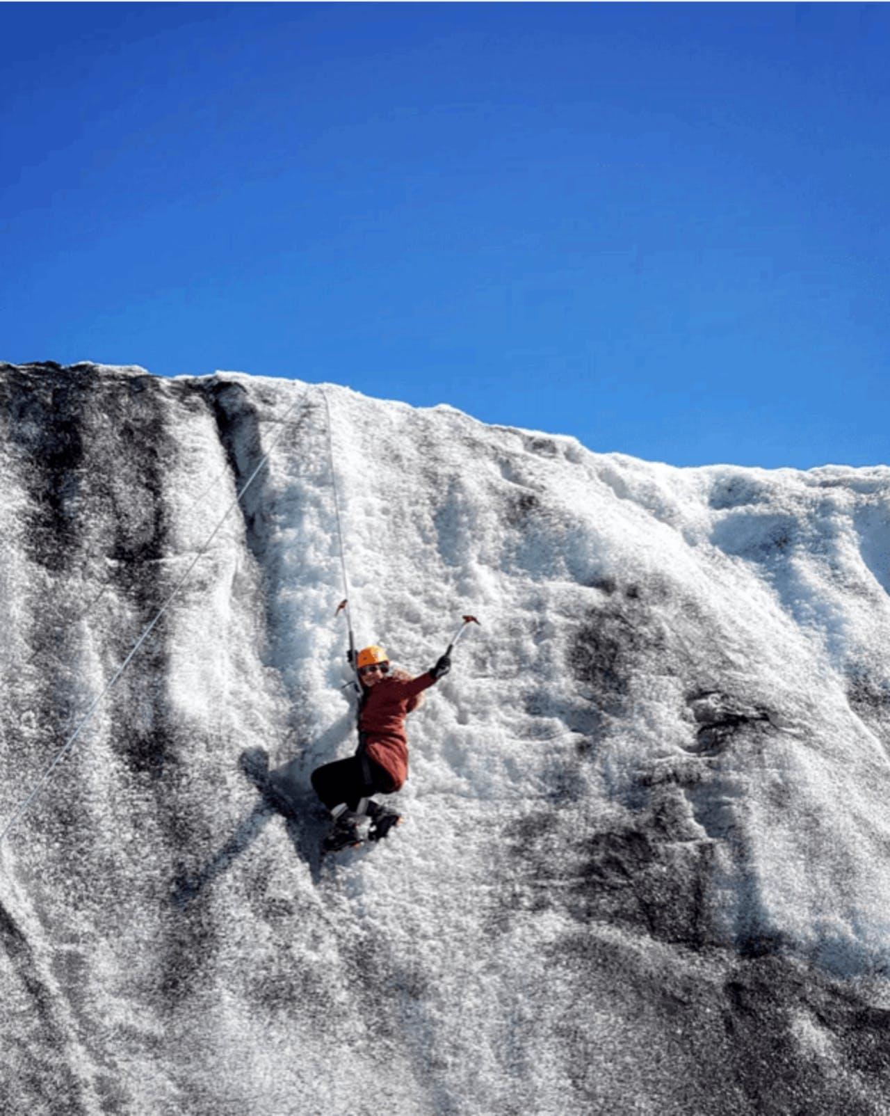 A man climbing on Sólheimajökull waving at the camera