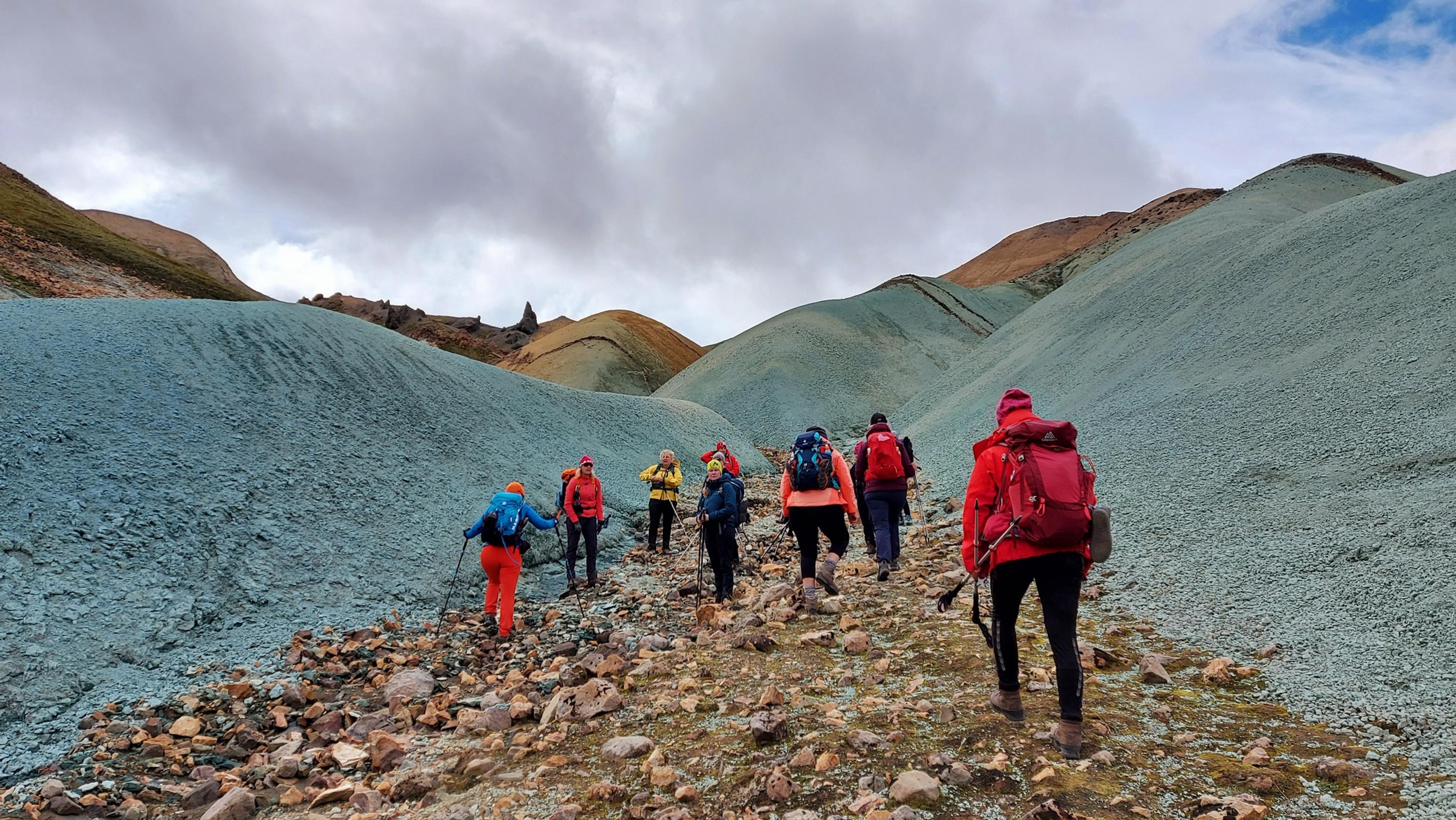 A sweeping view of Landmannalaugar's colorful mountains and valleys under a bright blue sky dotted with clouds.