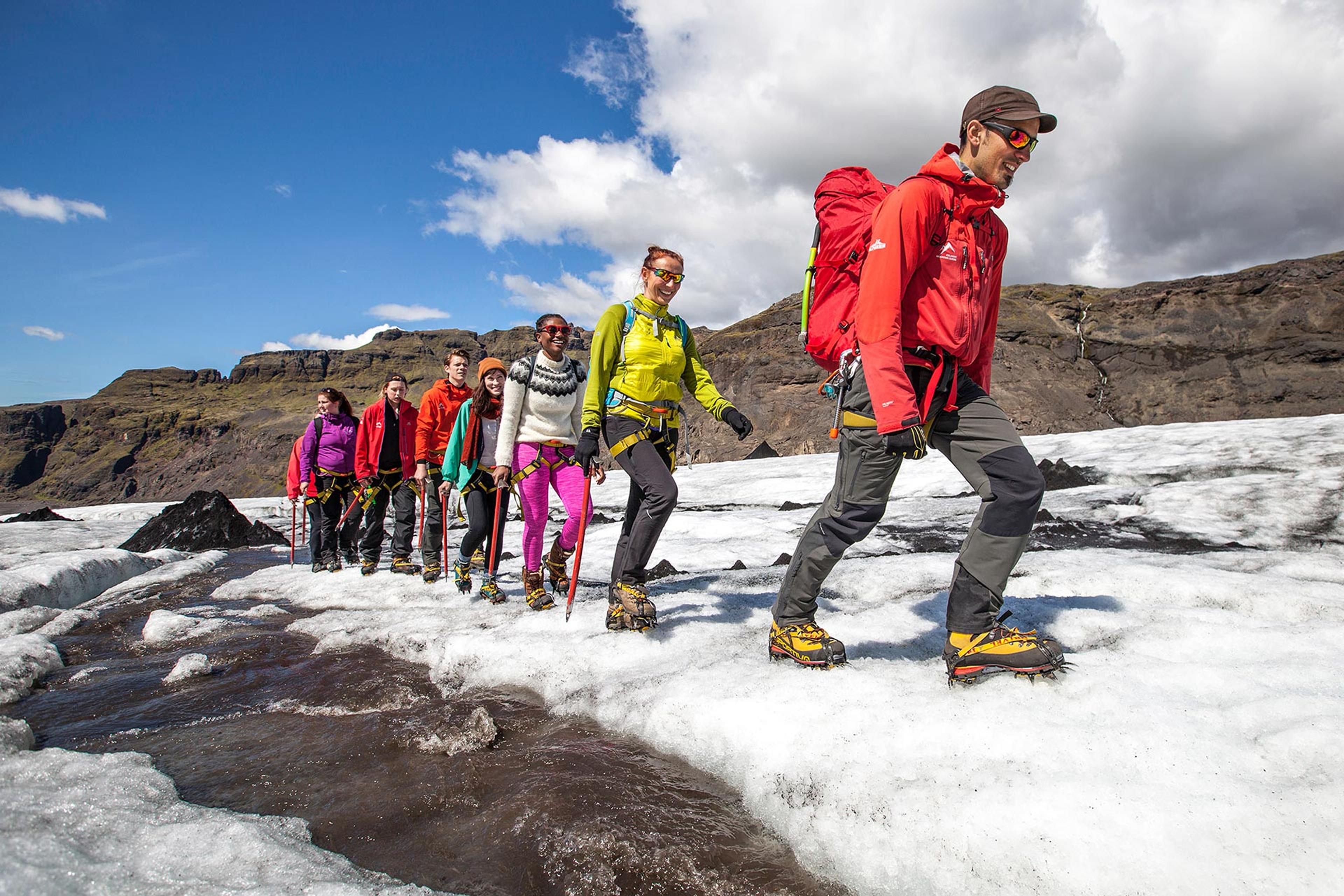 Mountain guide leading a group of people on a hike in the icy nature on a sunny day